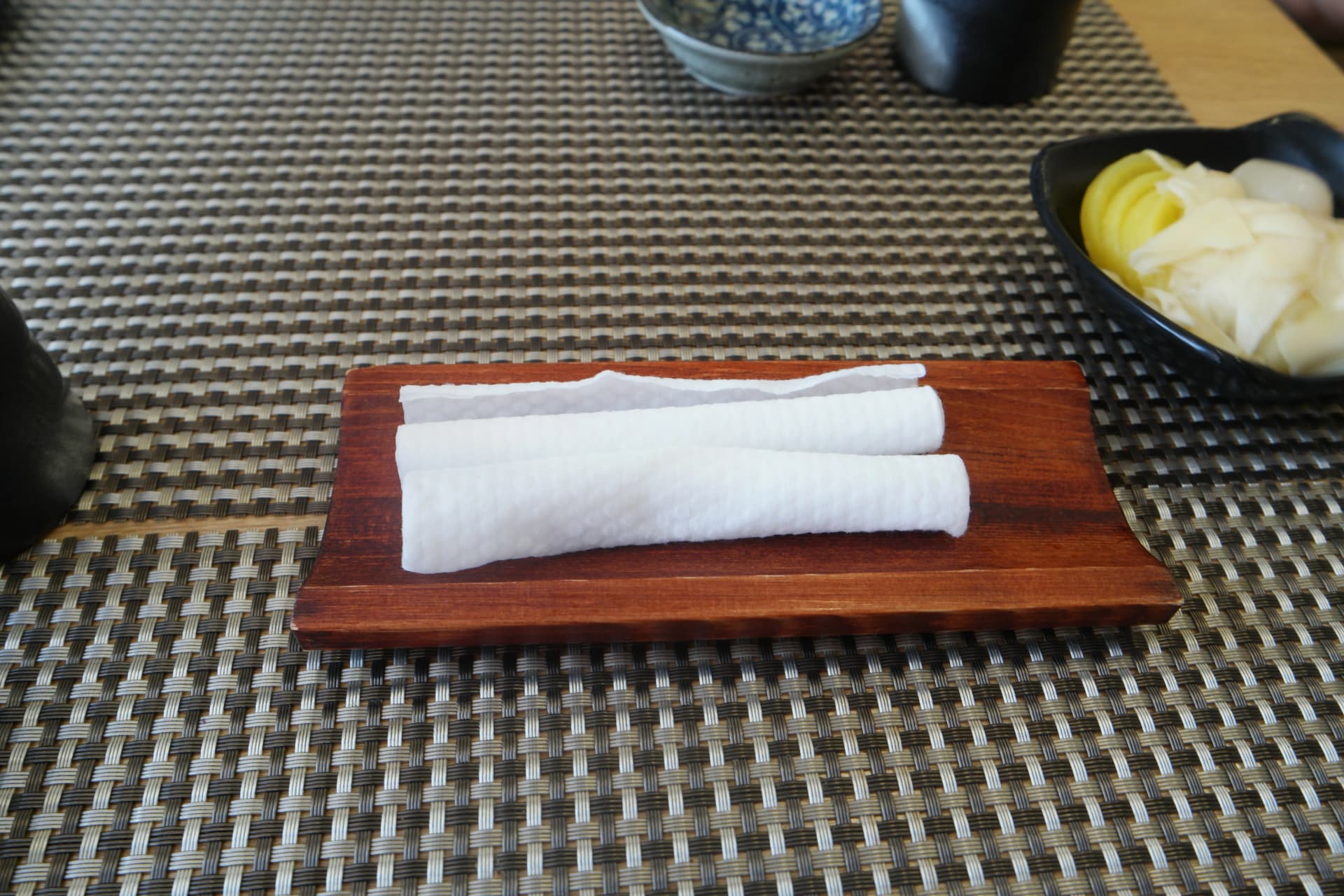 한국 초밥 전문점에서 식사 전에 제공되는 물수건 두 개가 나무 받침대 위에 놓인 모습 | 하이제이에스비