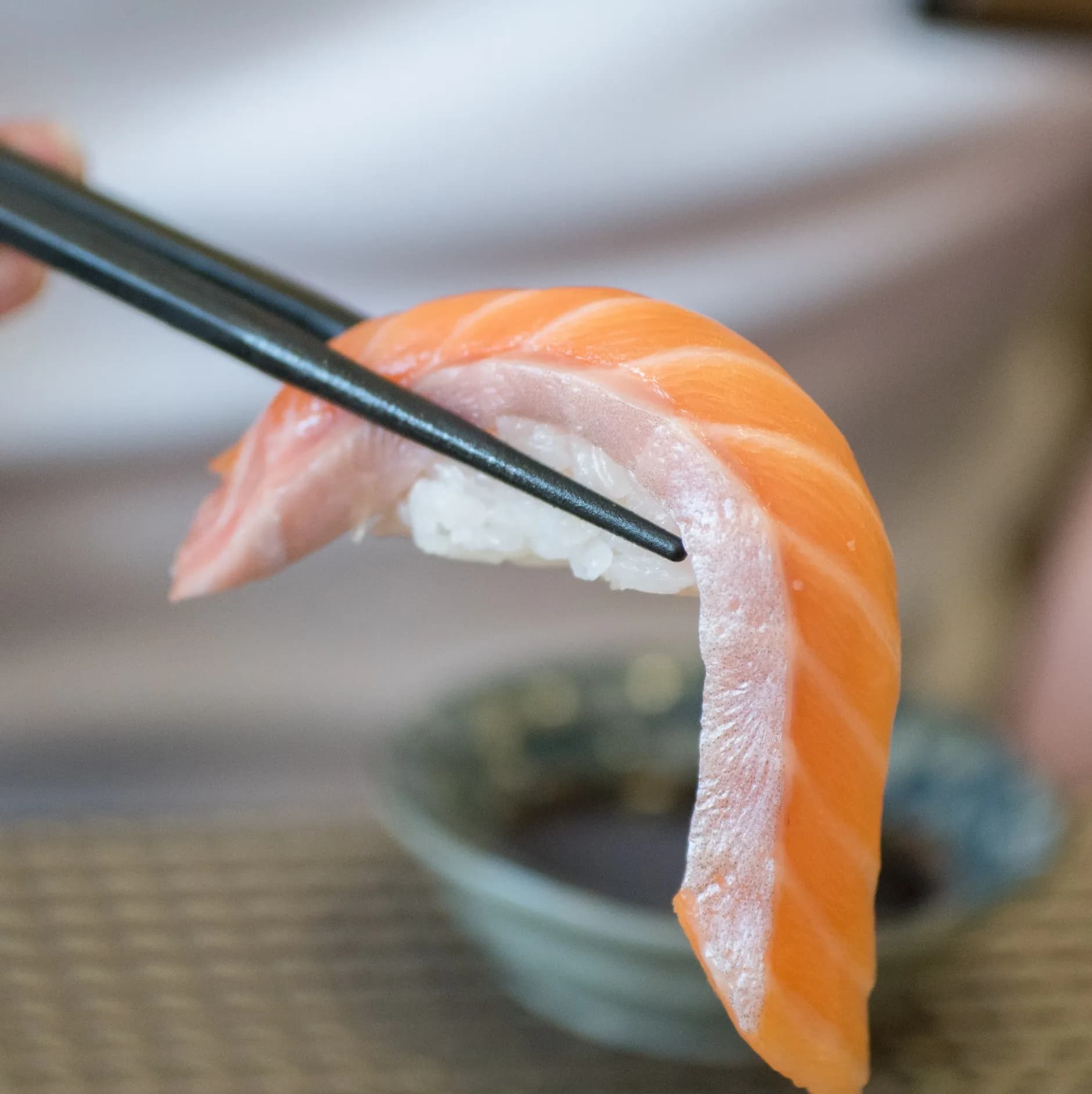 젓가락으로 집어올린 생연어 초밥 클로즈업 - 불을 대지 않은 싱싱한 날연어 | 하이제이에스비