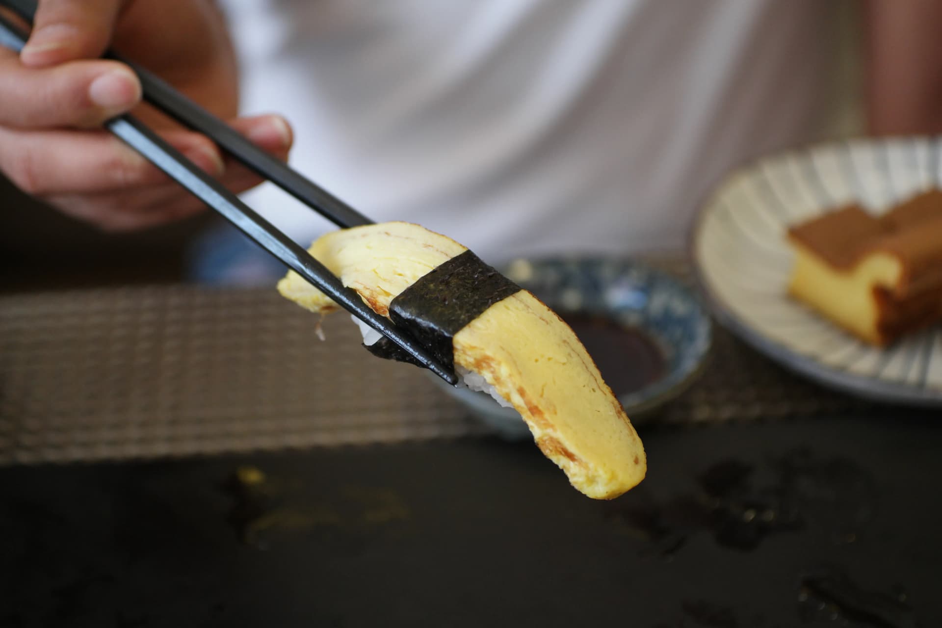 접시 위에 놓인 타마고 계란 초밥 클로즈업 - 노란 일본식 달걀말이가 밥 위에 올려진 모습 | 하이제이에스비