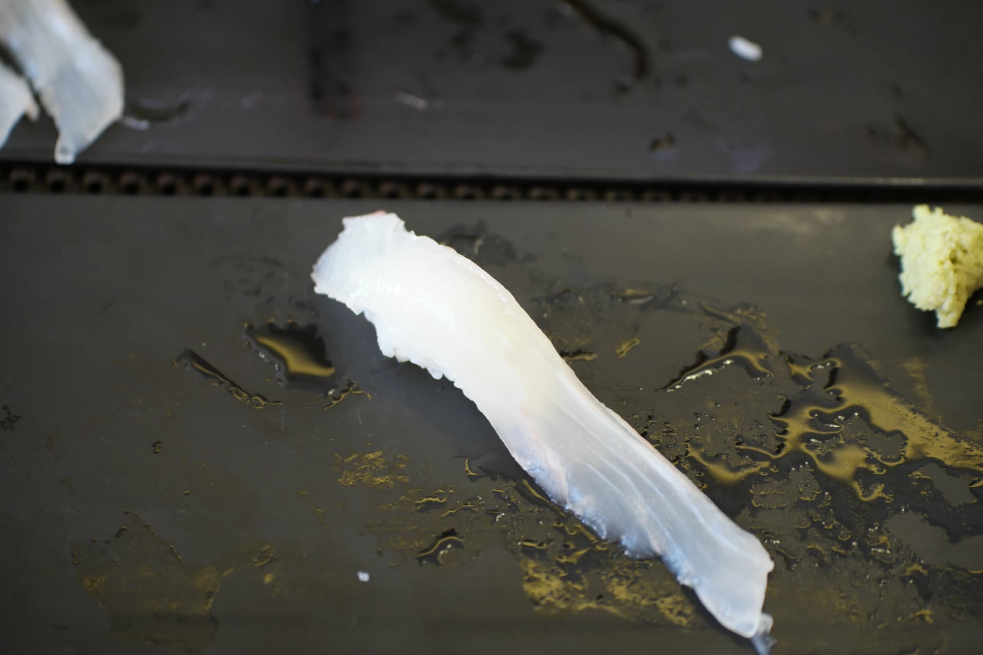 접시 위에 놓인 광어 초밥 클로즈업 - 하얗고 반투명한 광어살이 밥 위에 올려진 모습 | 하이제이에스비