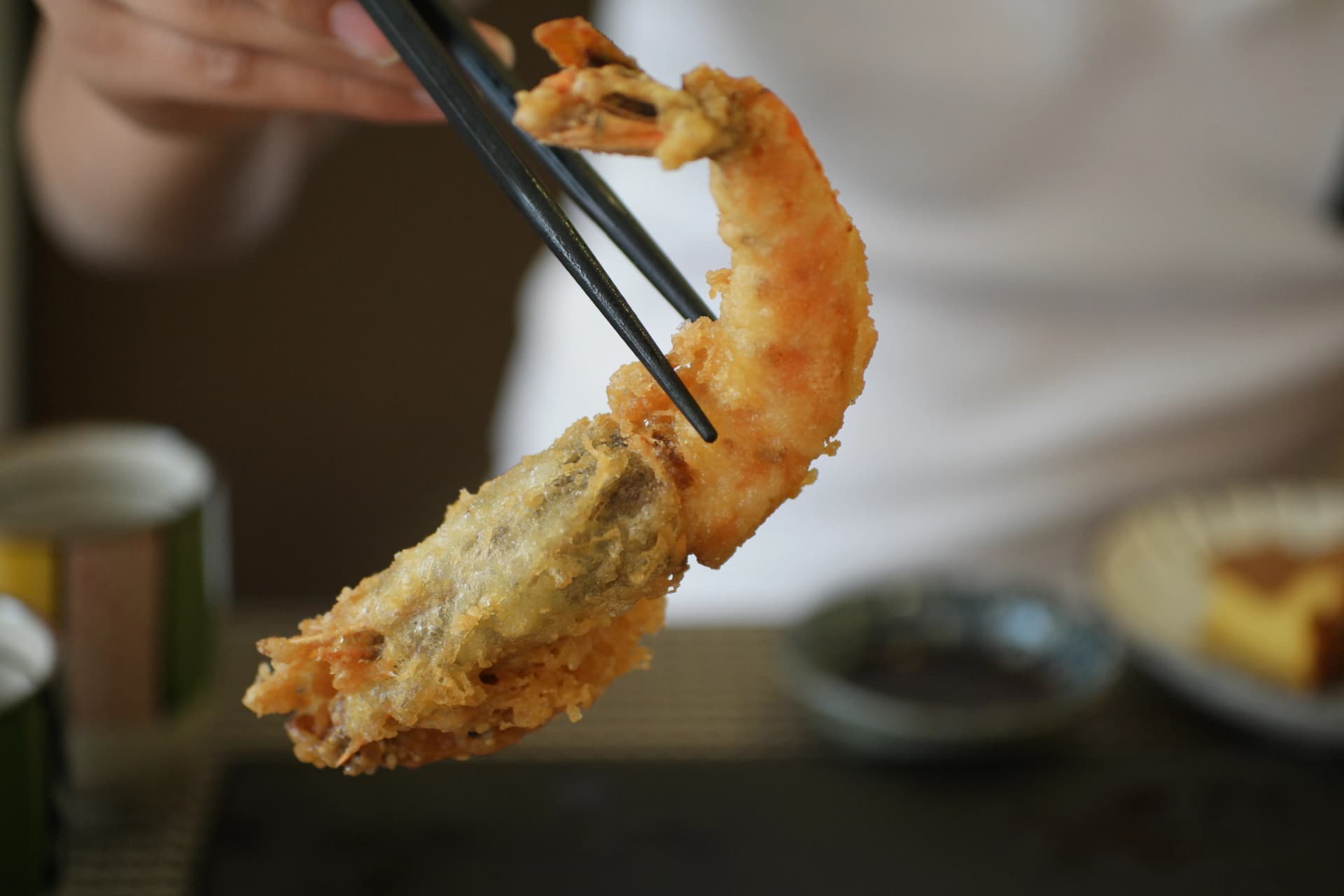 한국 초밥 세트의 새우튀김 클로즈업 - 큼직한 새우튀김을 젓가락으로 집어올린 모습 | 하이제이에스비