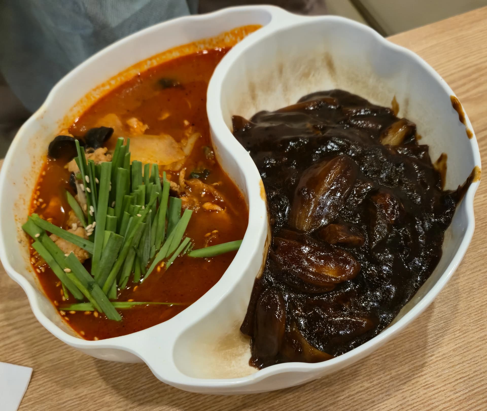 짬짜면을 위에서 내려다본 모습, 짬뽕 쪽에 부추와 깨가 올라가 있고 짜장 쪽에 양파가 보인다