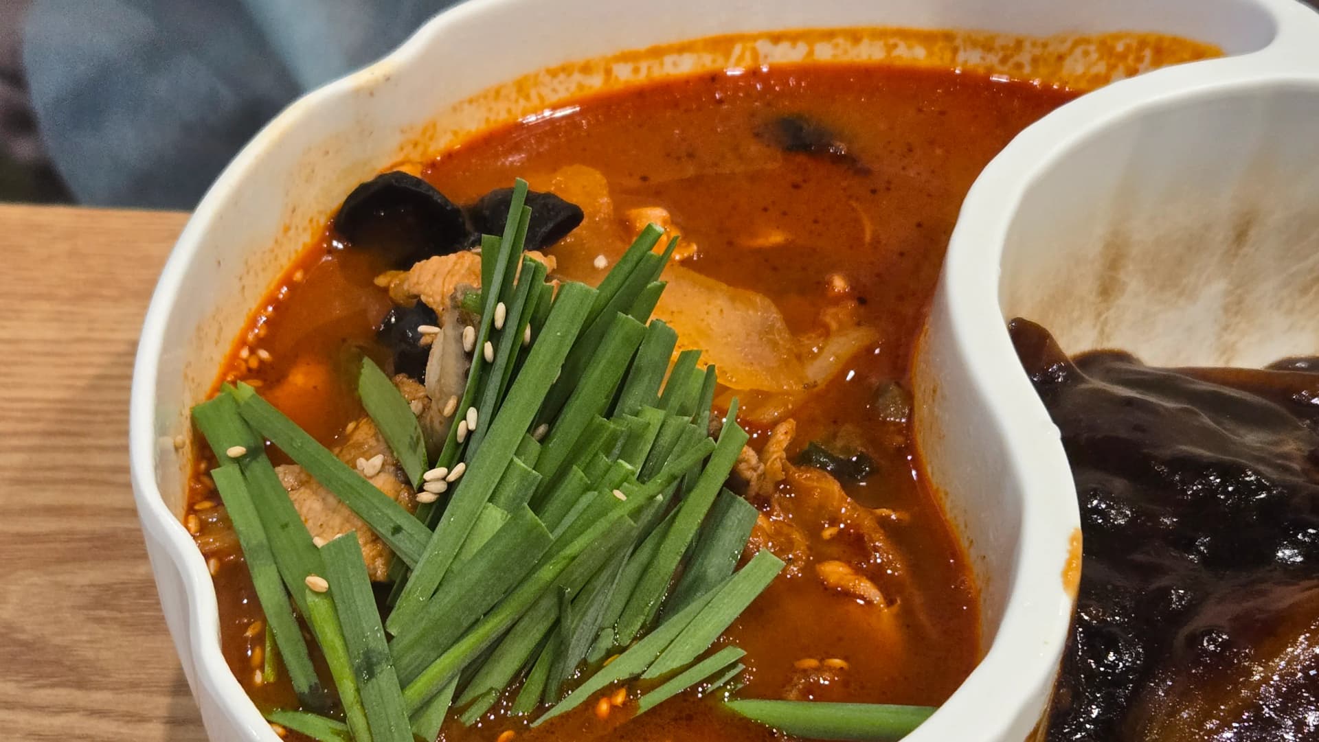짬짜면 짬뽕 쪽 클로즈업, 진한 주홍빛 국물에 부추 참깨 목이버섯 고기가 보이는 지옥짬뽕 2단계