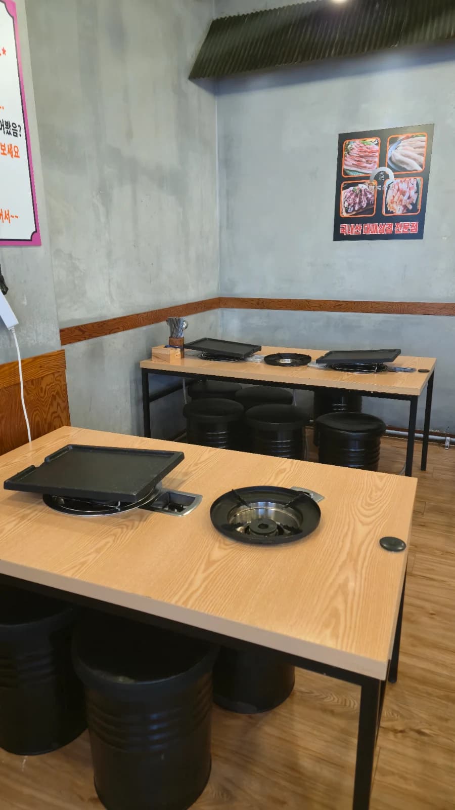 Interior del restaurante de daepae con mesas de plancha de hierro y asientos