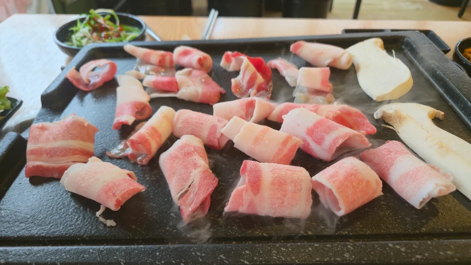 Panceta daepae chisporroteando sobre la plancha de hierro caliente