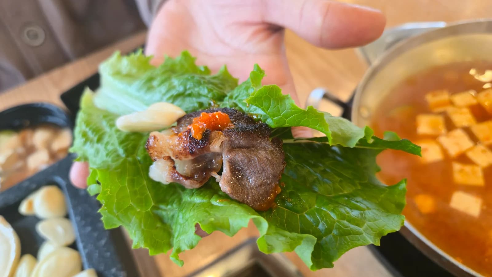 Hoja de lechuga con daepae asado, ajo y ssamjang armando un ssam coreano
