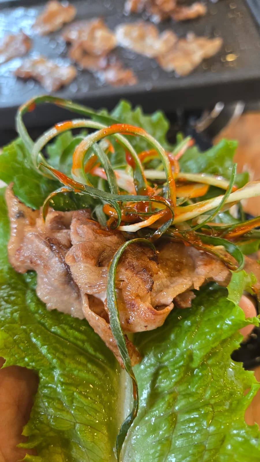Ssam de daepae samgyeopsal con abundante cebollín aliñado encima