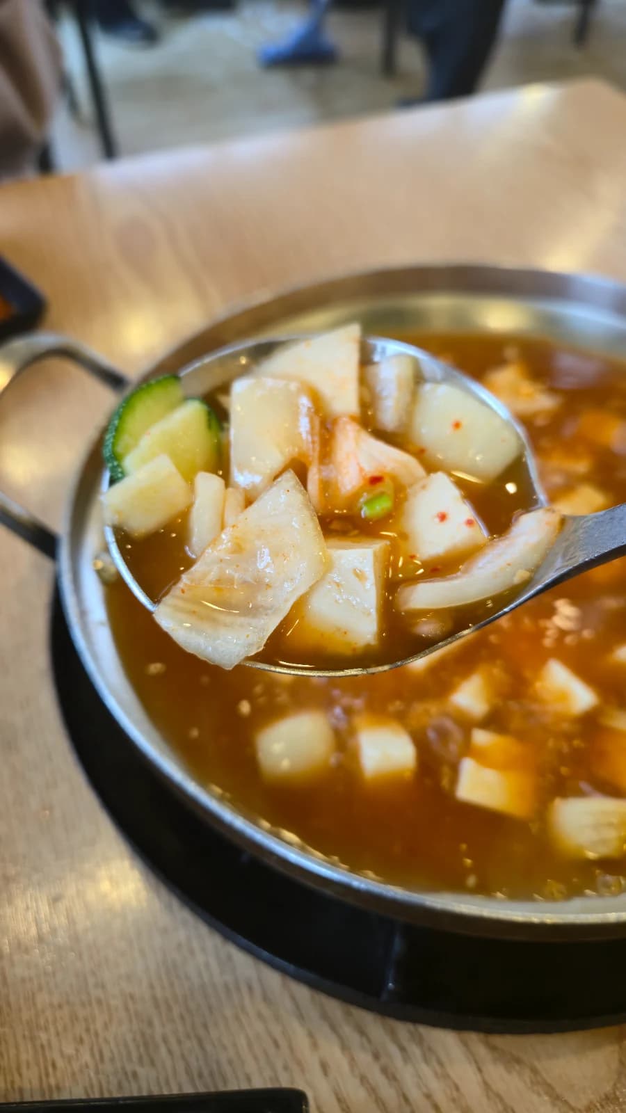 Cucharón sacando tofu y verduras de la sopa de doenjang