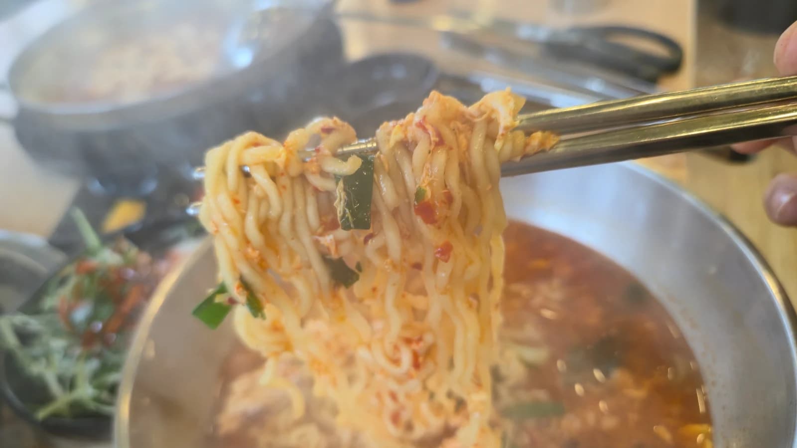 Palitos levantando fideos de ramen con huevo desde la olla