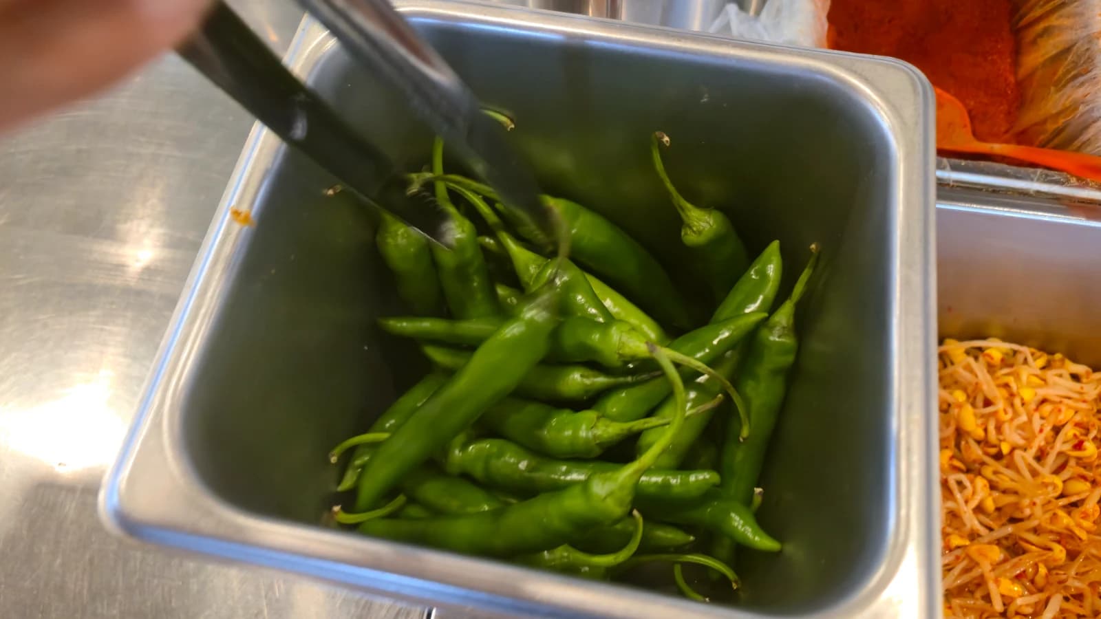 Ajíes verdes frescos apilados en el mesón de banchan self-service