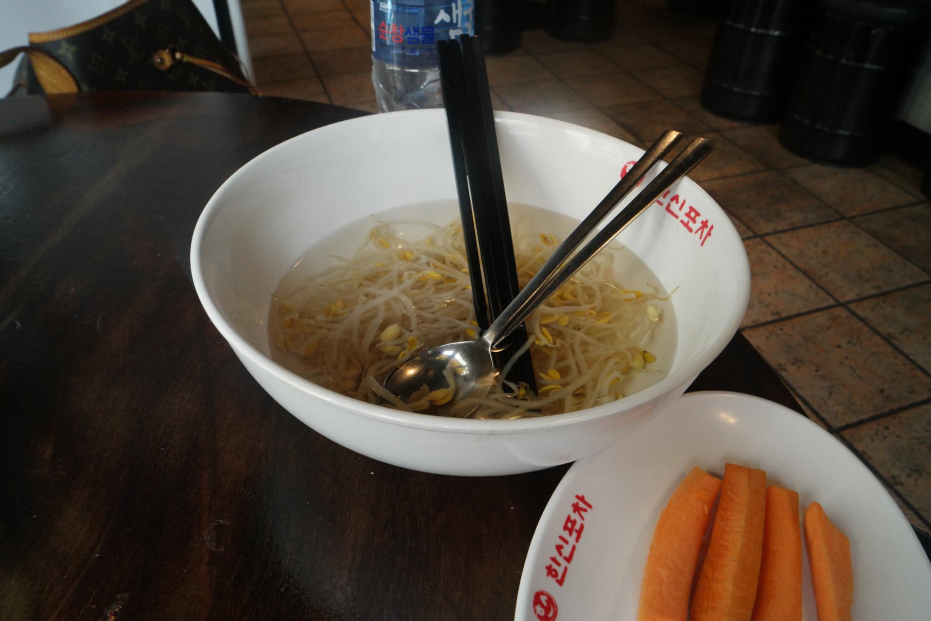 Caldo de brotes de soya de Hanshin Pocha servido en un bowl blanco, con palitos y cuchara al costado