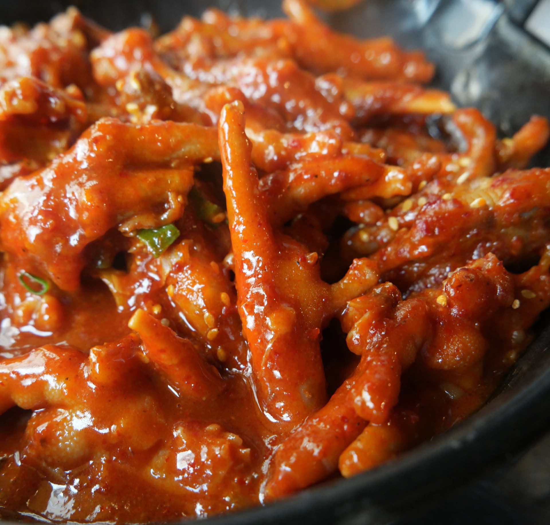 Primer plano del dakbal con caldo ya reducido, con salsa espesa y pegajosa cubriendo cada pata de pollo