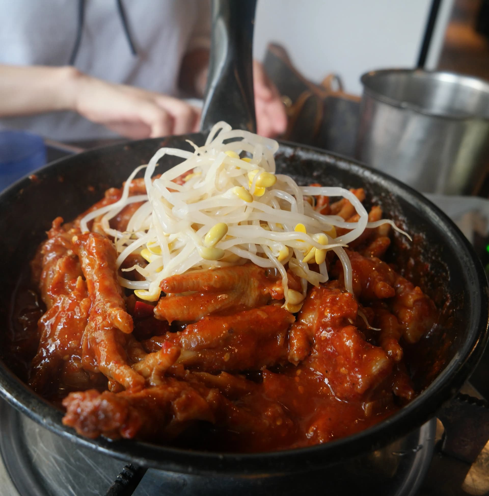 Montón de brotes de soya blancos colocados encima de patas de pollo rojas y bien picantes