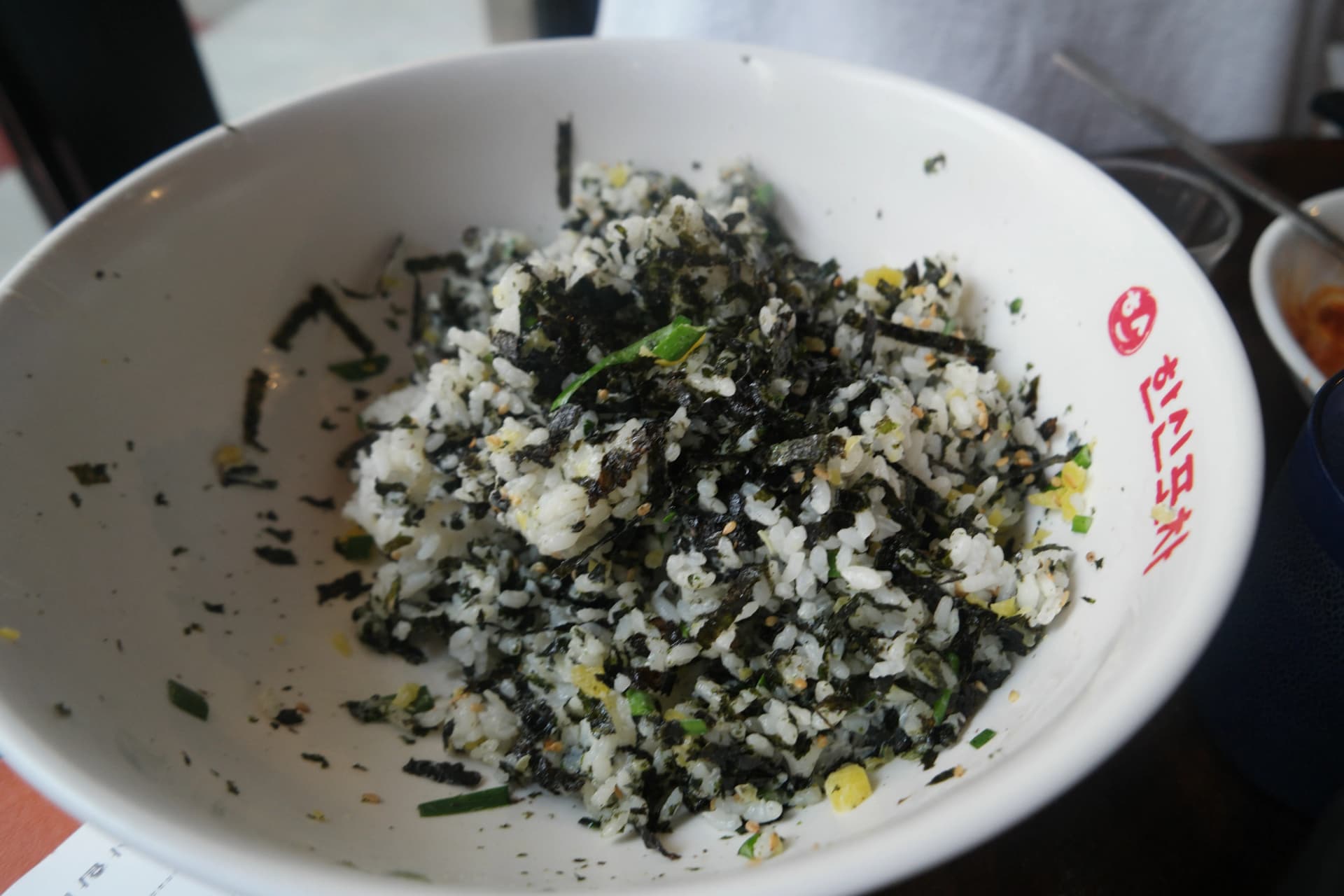 Ingredientes del jumokbap mezclados con la mano, con las hojuelas de alga metiéndose entre los granos de arroz