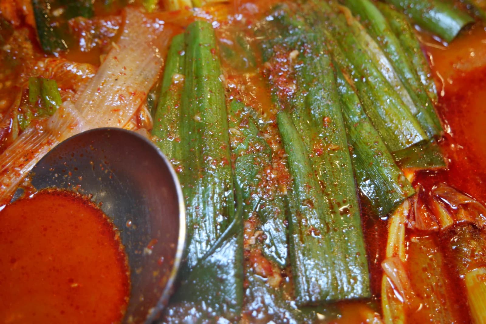 Close-up of dakbokkeumtang broth showing red oil slick from gochujang and chili flakes on the surface