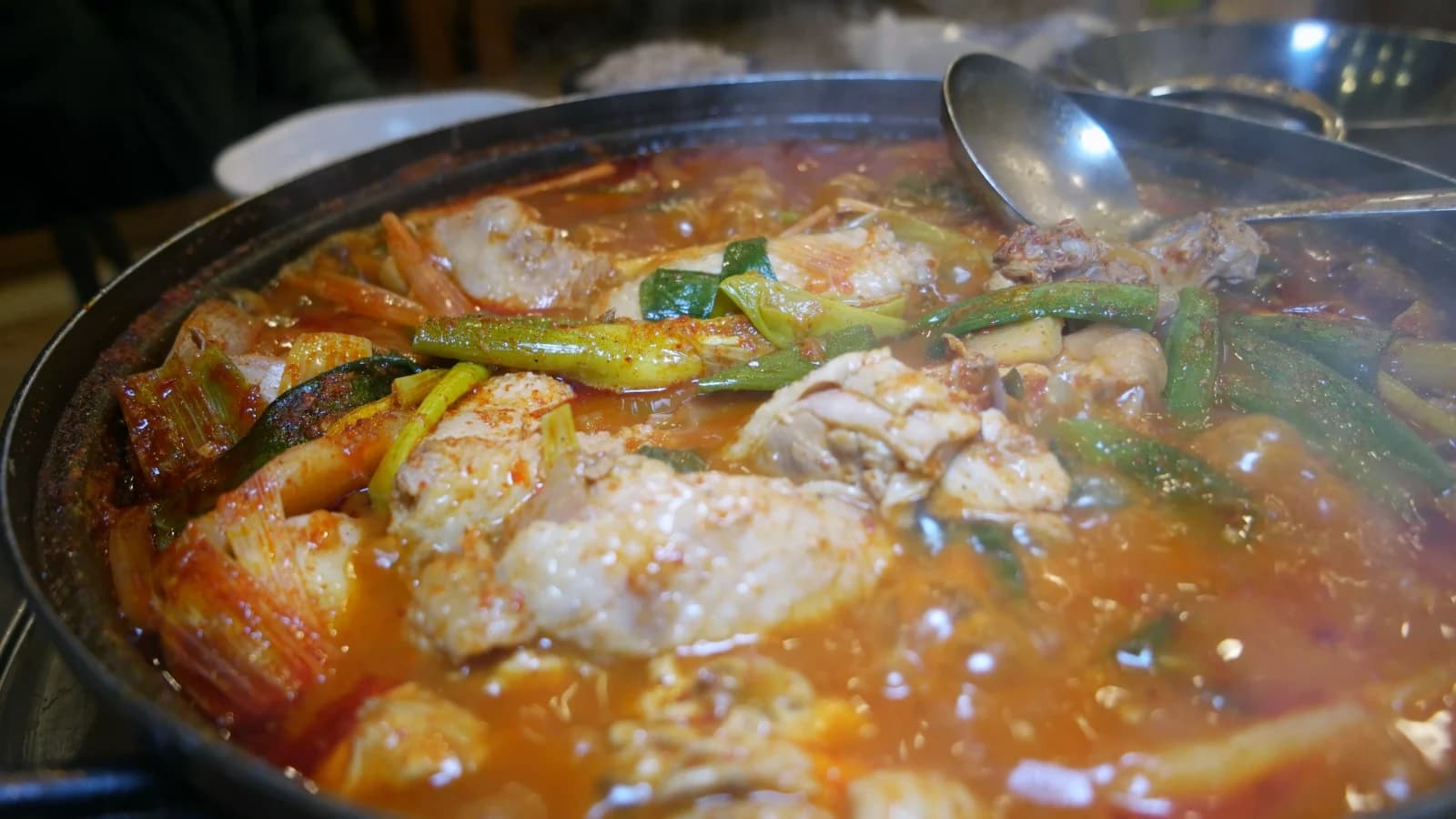 Dakbokkeumtang at a rolling boil with large chicken pieces floating to the surface
