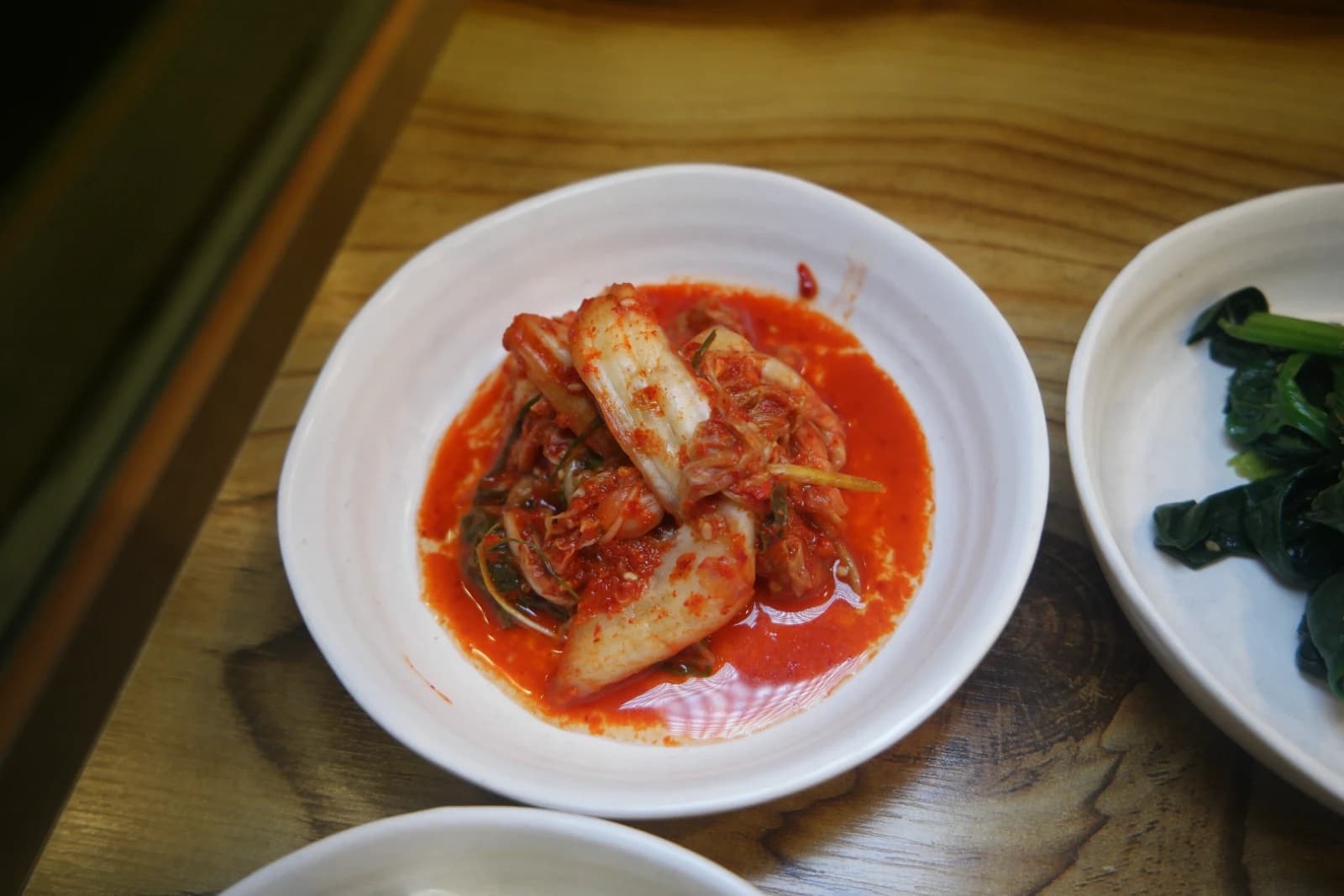 Well-fermented napa cabbage kimchi with tangy juices pooling on the plate