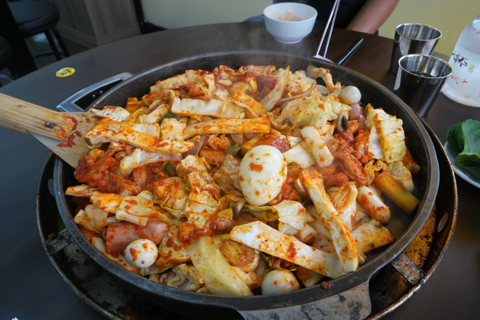 Dakgalbi ikikaangwa kwenye sahani ya chuma: tteok, yai, uyoga na spam vikichanganyika na gochujang | 하이제이에스비