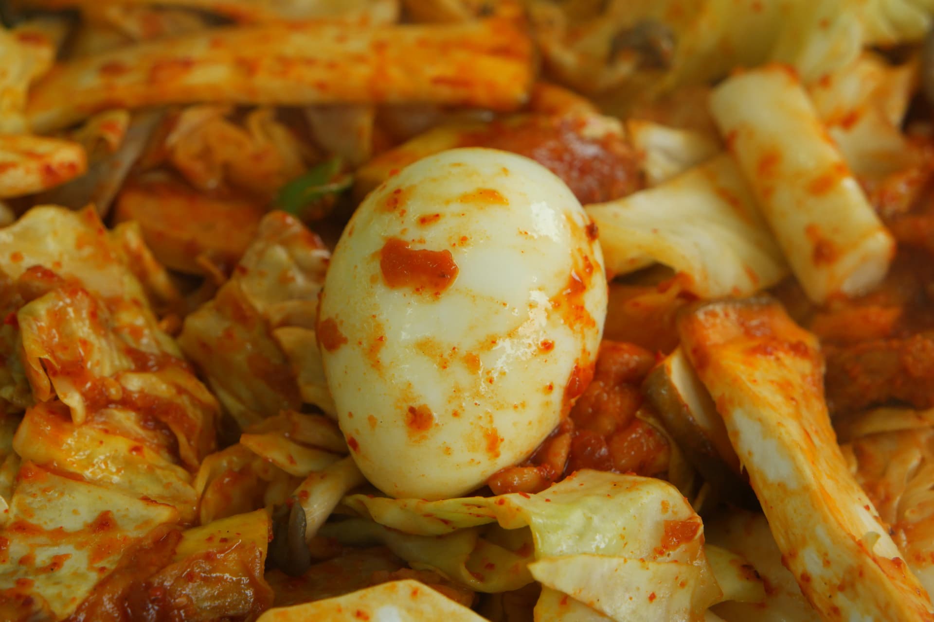 Yai la kuchemsha katikati ya sahani ya chuma, likizungukwa na mchanganyiko wa pilipili wa dakgalbi | 하이제이에스비