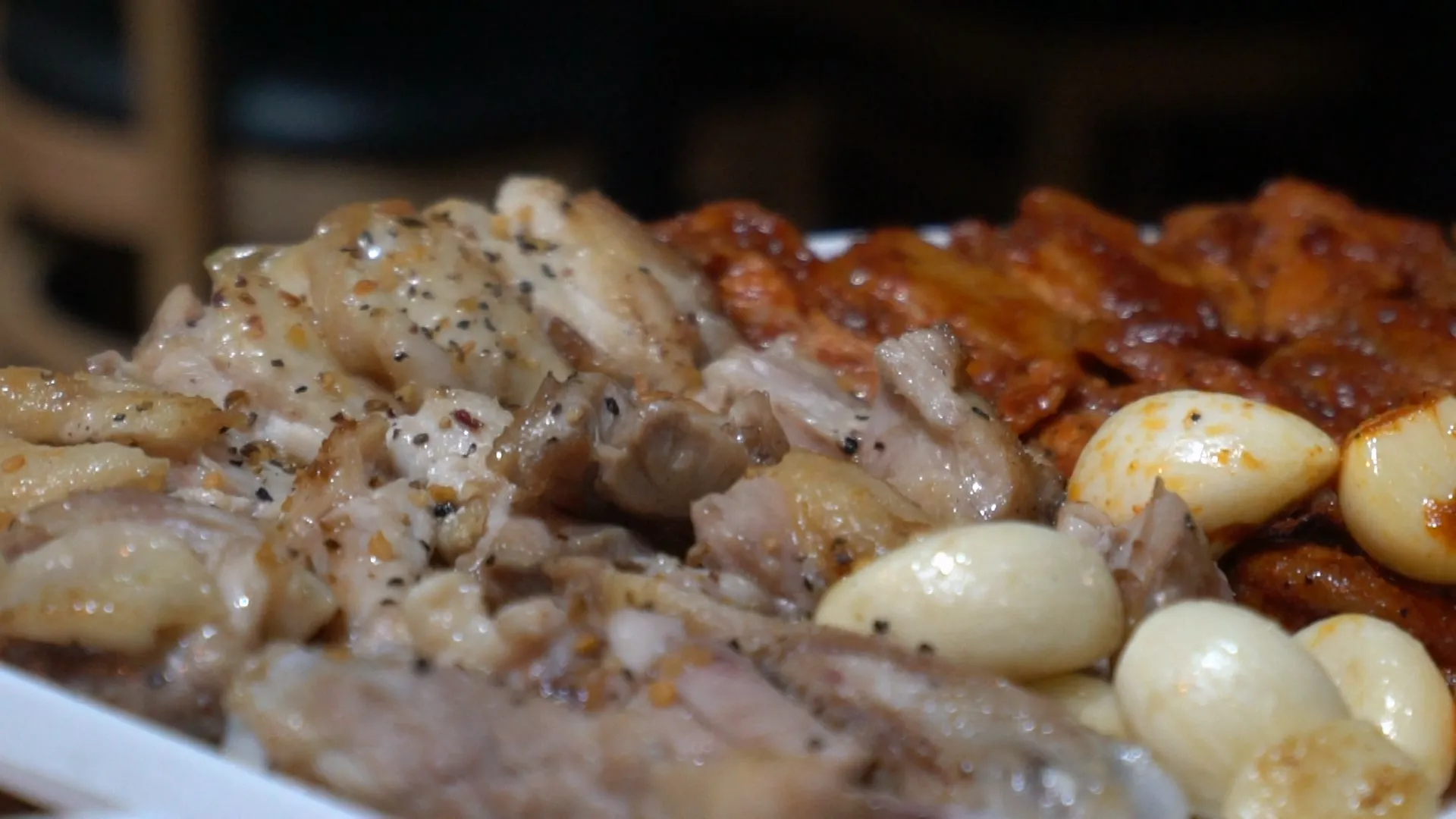 Close-up of salt and pepper seasoned charcoal grilled chicken with whole garlic cloves on the side