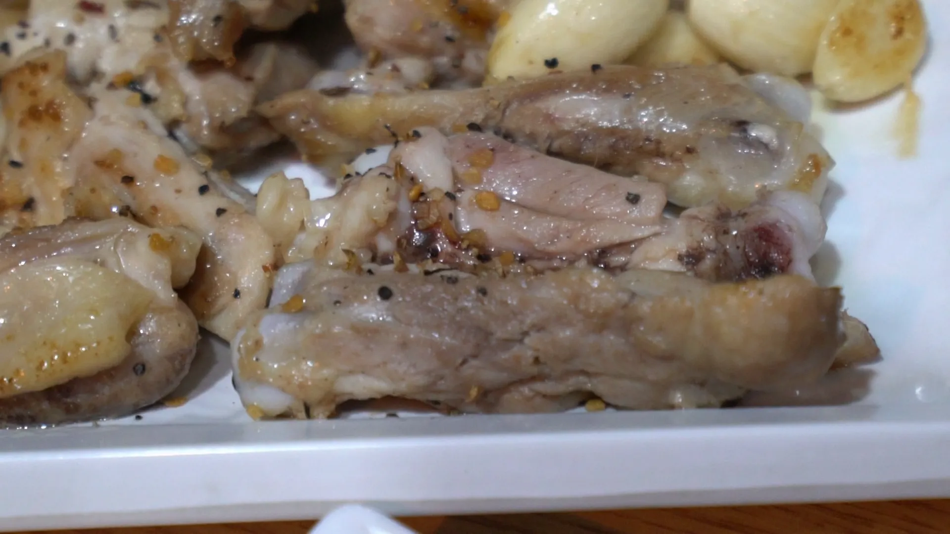 Cross-section of pre-seared salt grilled chicken showing pepper flakes and minced garlic pressed into the meat