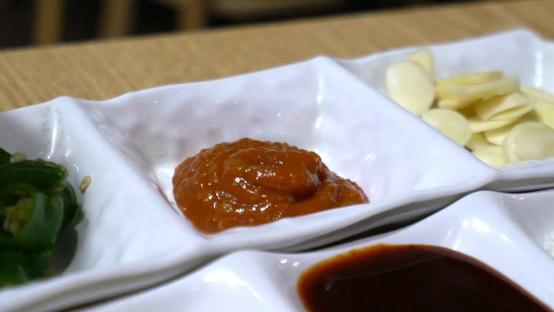 Thinly sliced raw garlic on a plate served as a side for smoky charcoal grilled dakgalbi