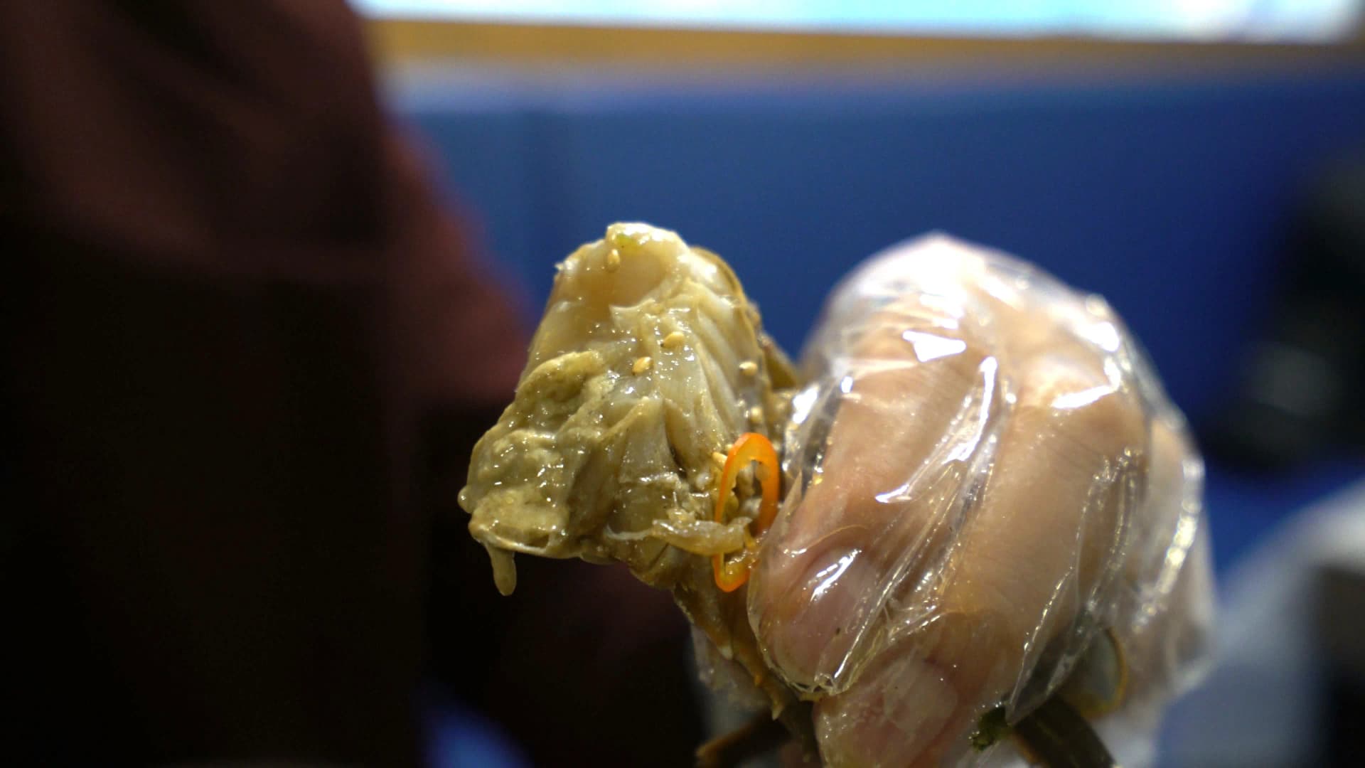 Fingers pressing a crab leg to push out a whole piece of soy-cured crab meat in one go