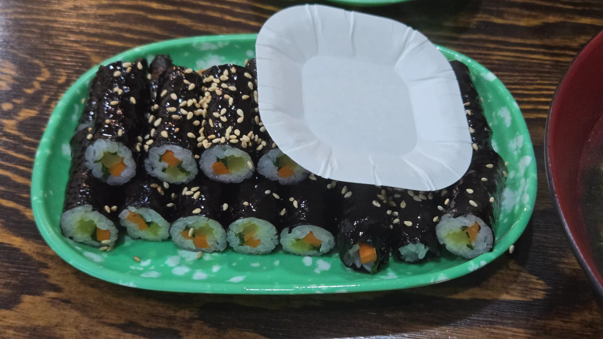 ಹಸಿರು ತಟ್ಟೆ ಮೇಲೆ ಎಳ್ಳು ಹಾಕಿದ ಕೊರಿಯನ್ ಕೊಮಾ ಗಿಂಬಾಪ್ – ಪುಟ್ಟ ಅಕ್ಕಿ ರೋಲ್‌ಗಳು | 하이제이에스비