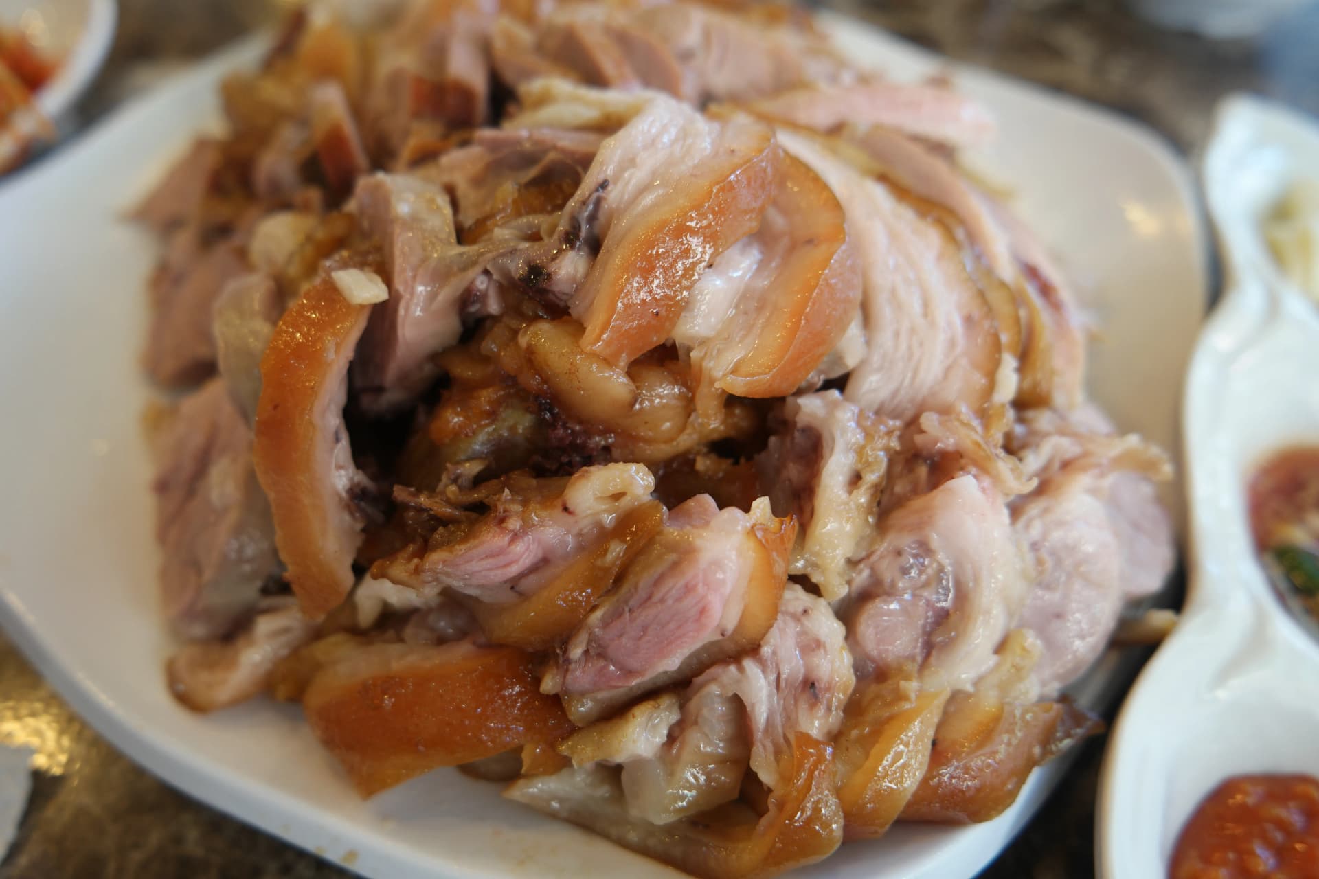 Klassisk koreansk jokbal — skinnende brune grisefødder kogt i sojasauce, skåret i skiver på tallerken | 하이제이에스비