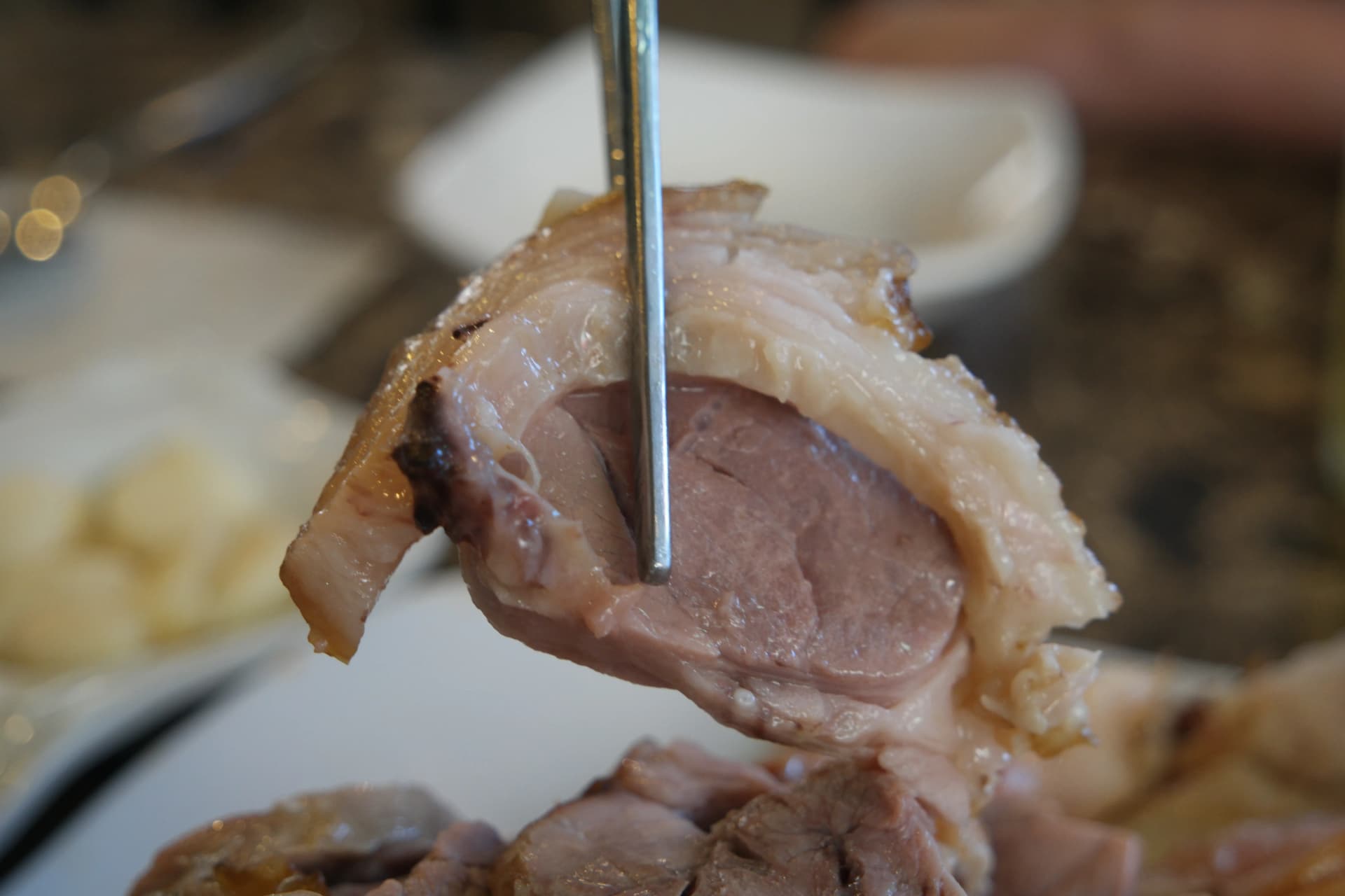 Nærbillede af et stykke jokbal på spisepinde — lag af sej svær og blødt kød synlige i tværsnit | 하이제이에스비