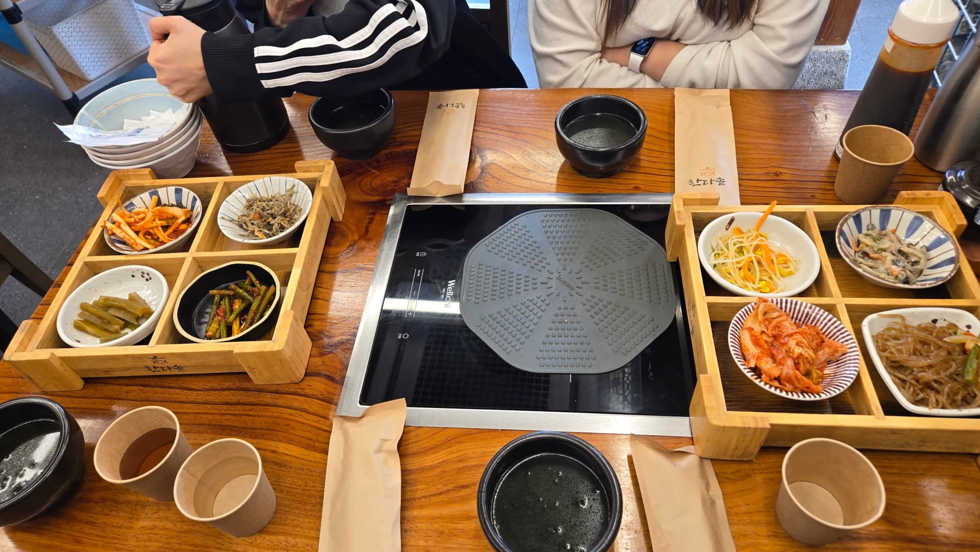 δύο δίσκοι με συνοδευτικά πάνω στο τραπέζι με επαγωγική εστία έτοιμο κορεάτικο τραπέζι | 하이제이에스비