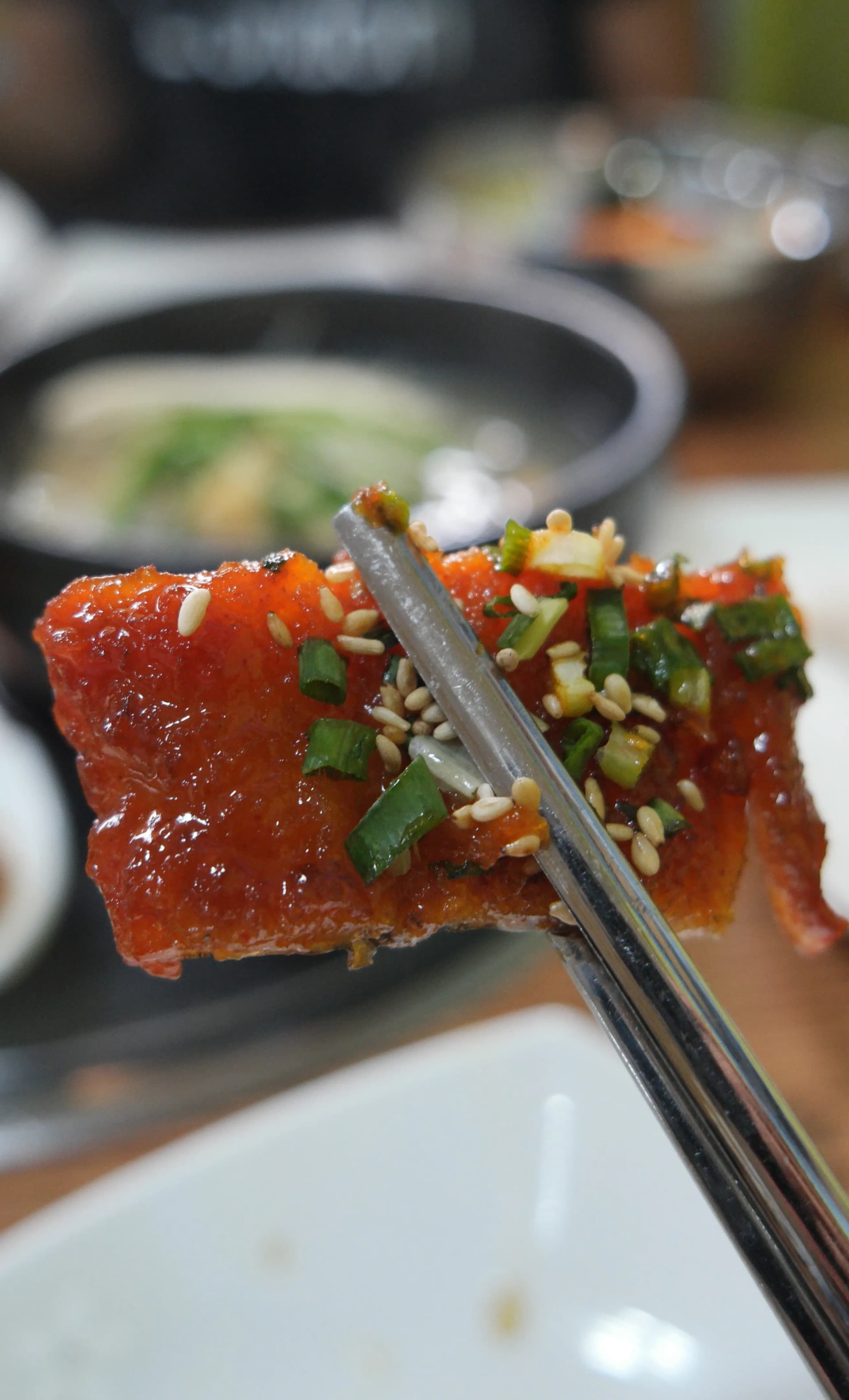 عيدان تلتقط قطعة هوانغتيه جوريم بالصلصة والسمسم — لقمة فوق الأرز