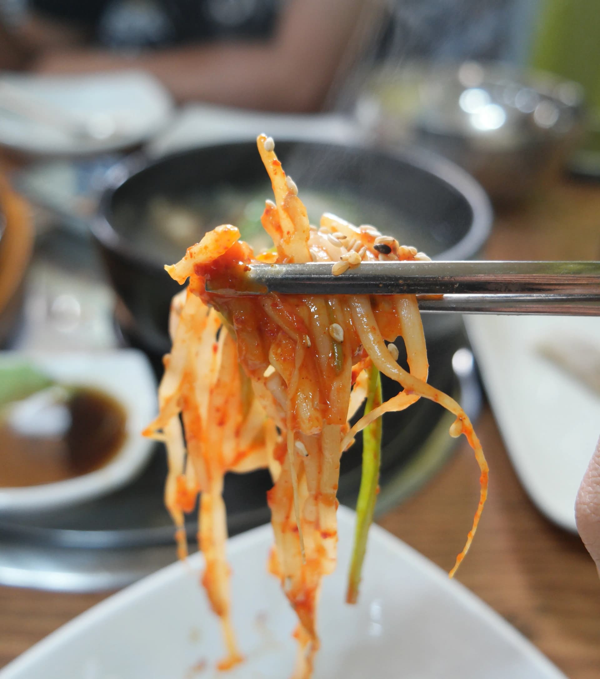 براعم فاصوليا مشبّعة بالصلصة الحارة تُلتقَط بالعيدان من طبق هوانغتيه