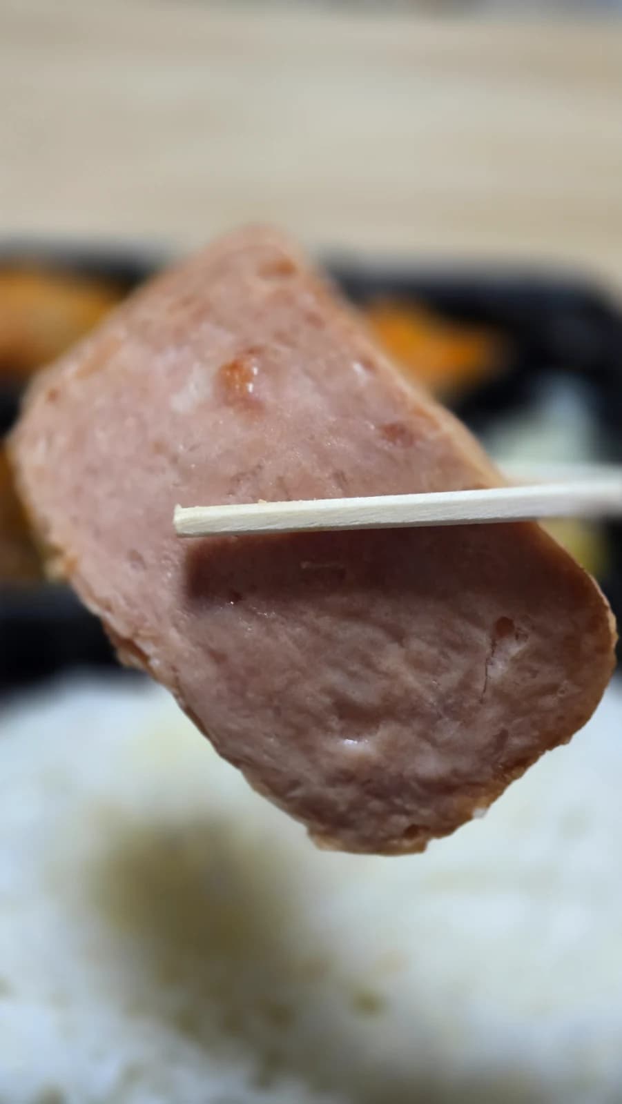 スパムを箸で持ち上げた厚みのクローズアップ 塩気控えめな印象