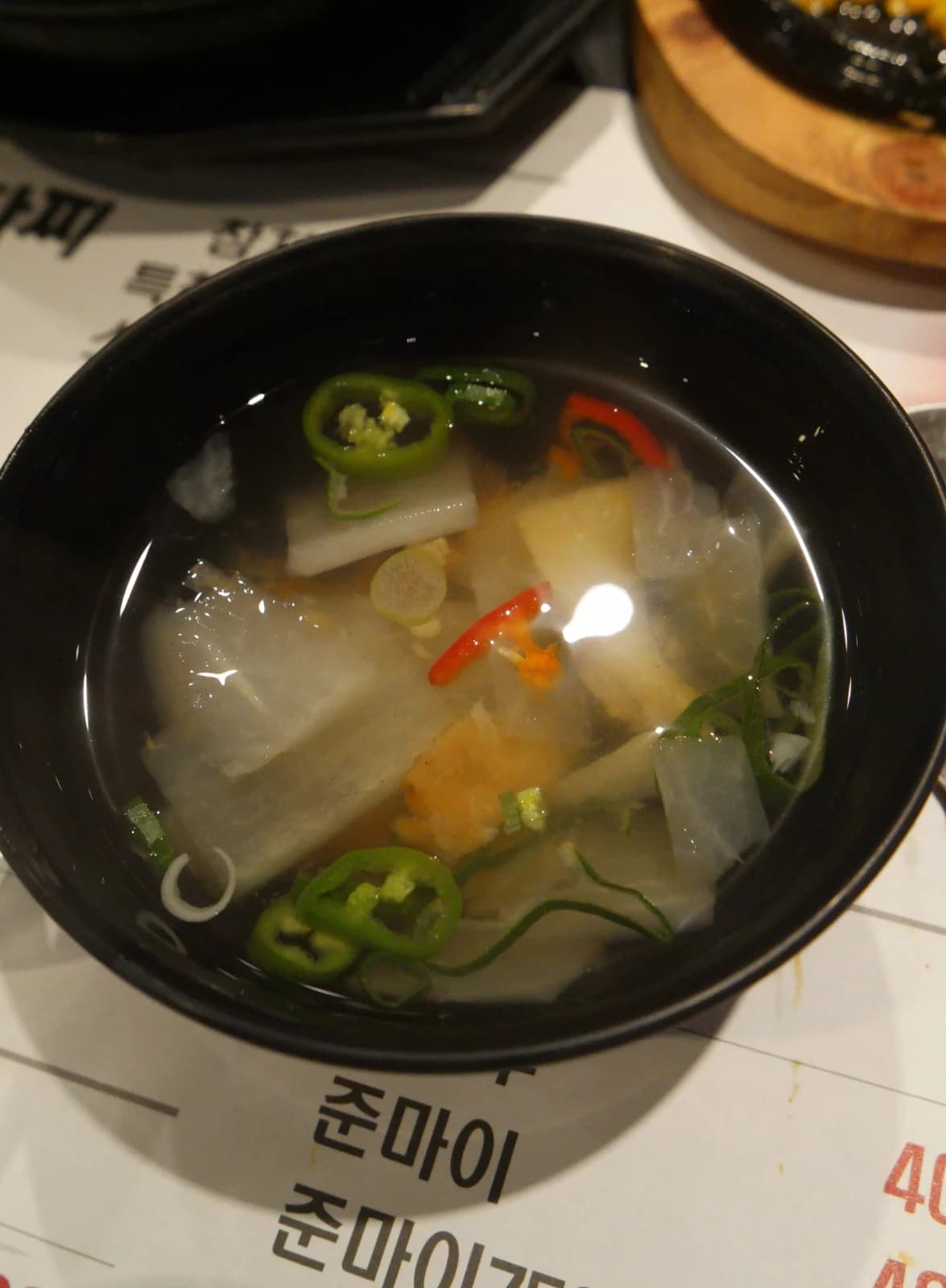Mini bowl of hwangtae-guk dried pollack soup with clear broth, radish slices, and chili pepper pieces