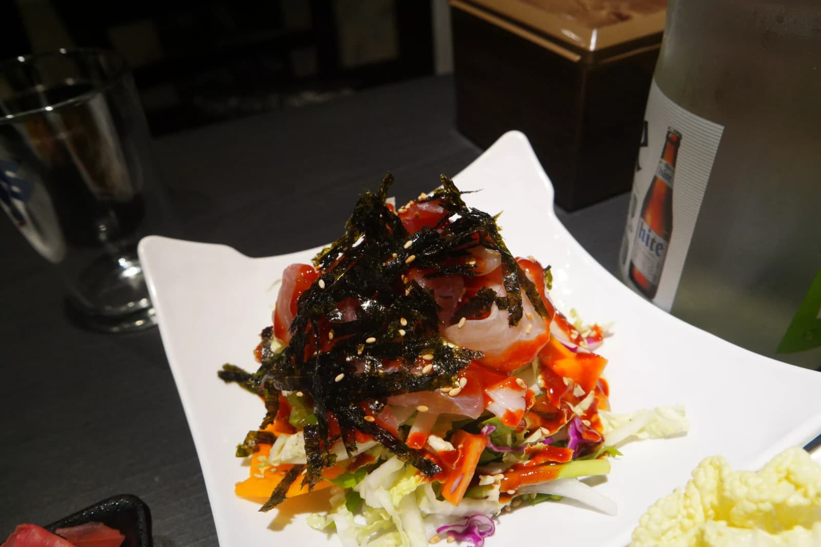 Korean spicy raw fish salad piled high with sashimi slices, red chili vinegar sauce, and shredded seaweed over cabbage and carrots