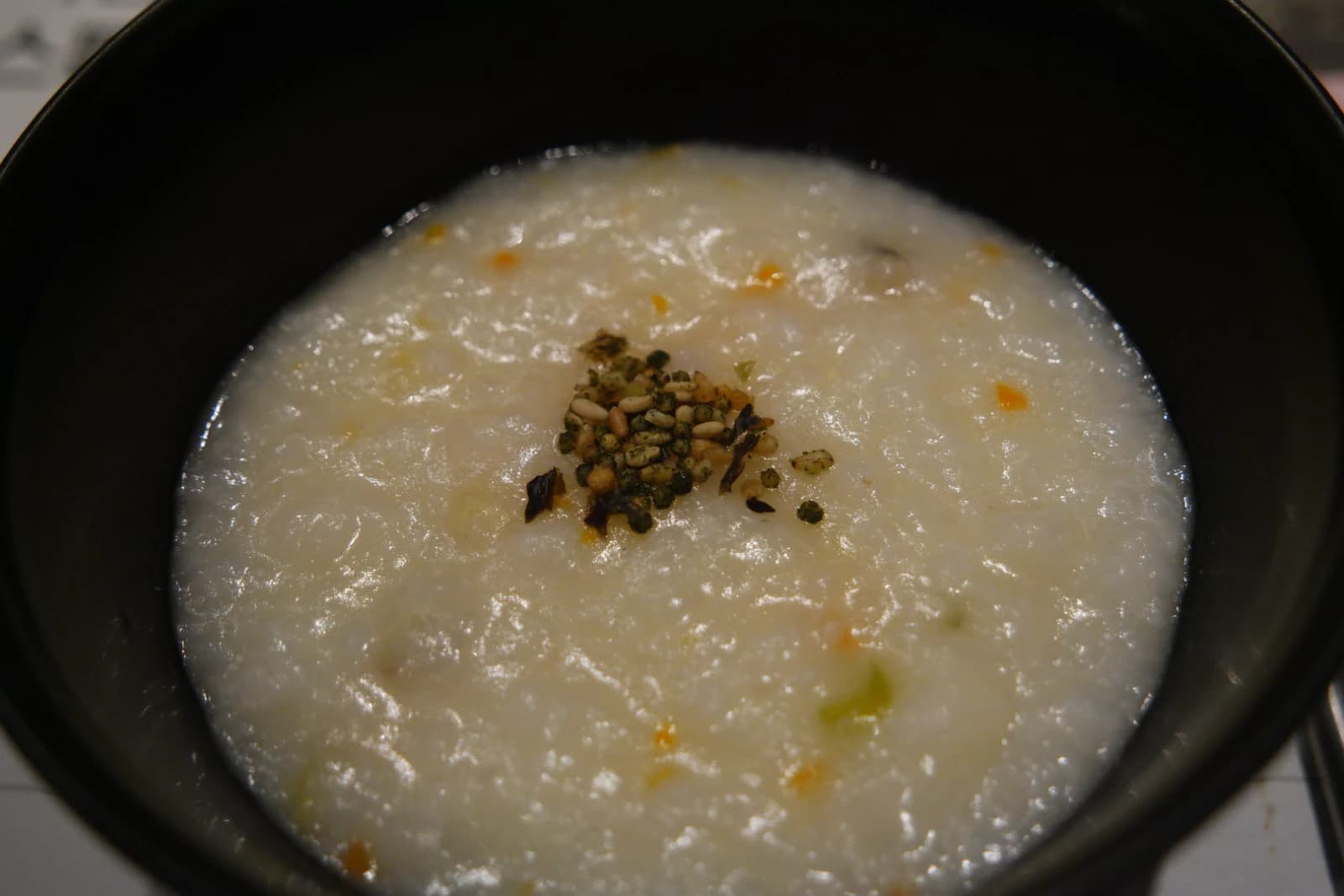 Close-up of abalone porridge showing orange specks from abalone innards mixed into the rice
