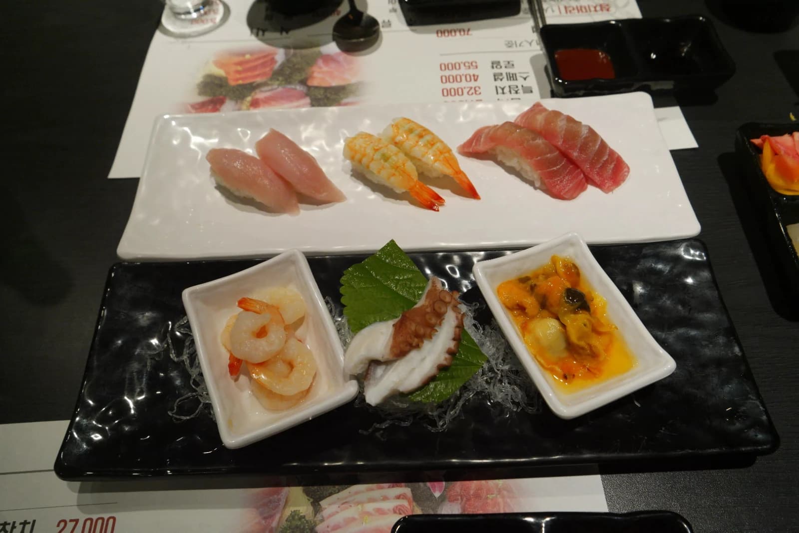 Sushi platter alongside small bowls of shrimp, octopus, and sea squirt covering the entire table