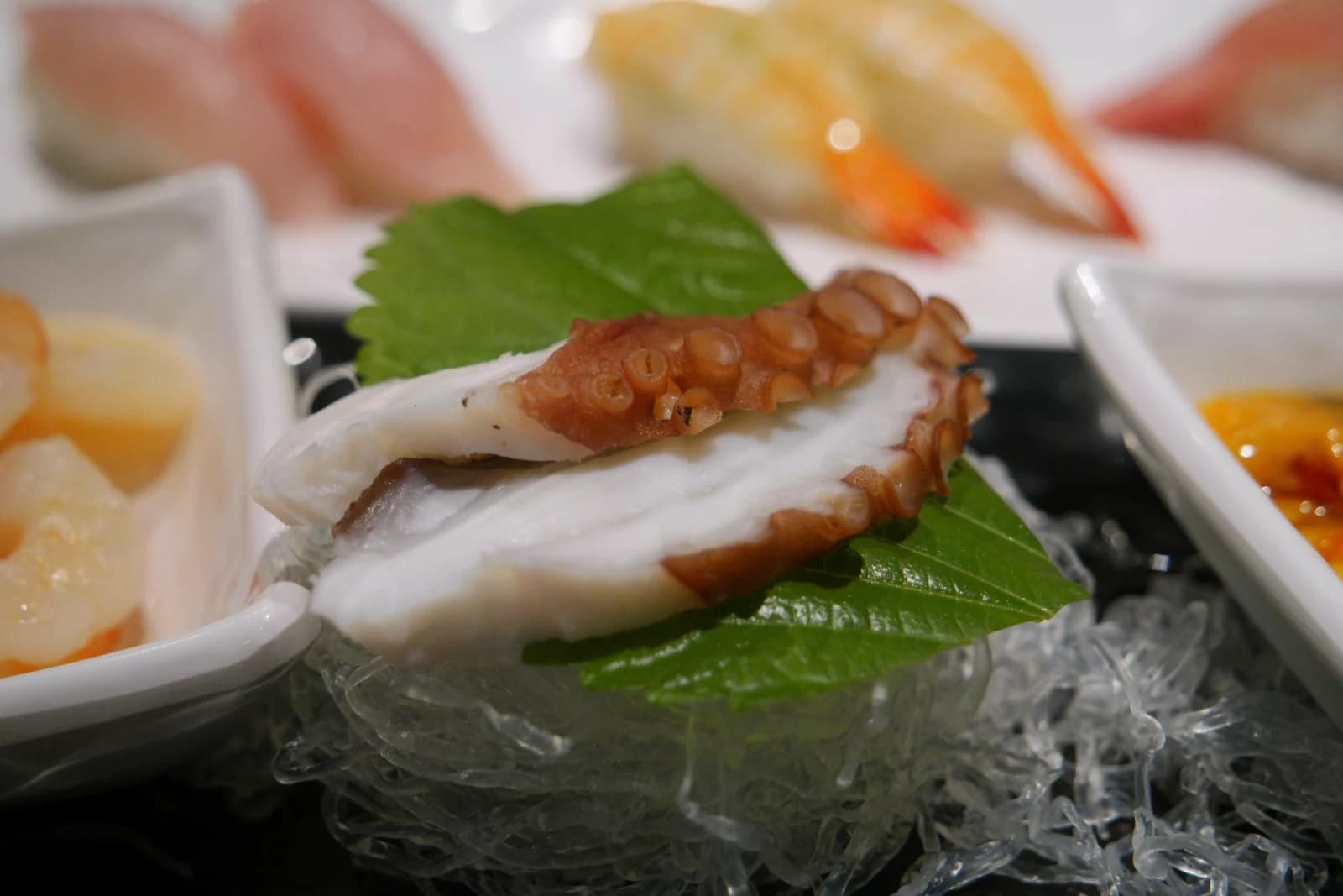 Thick octopus tentacle slice served on a perilla leaf with visible suction cups