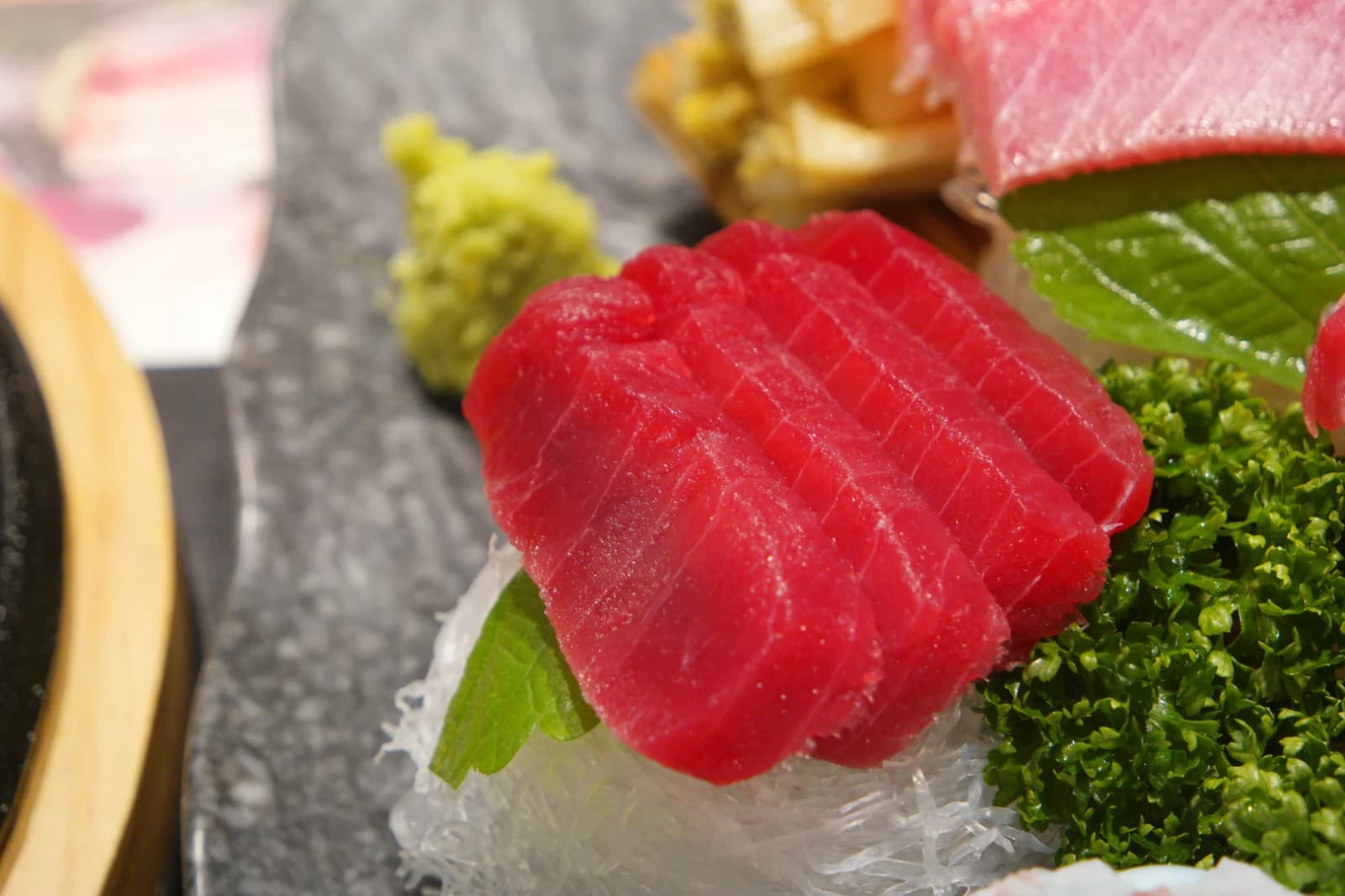 Lean red tuna sashimi next to a bright green wasabi mound, vivid red and green contrast