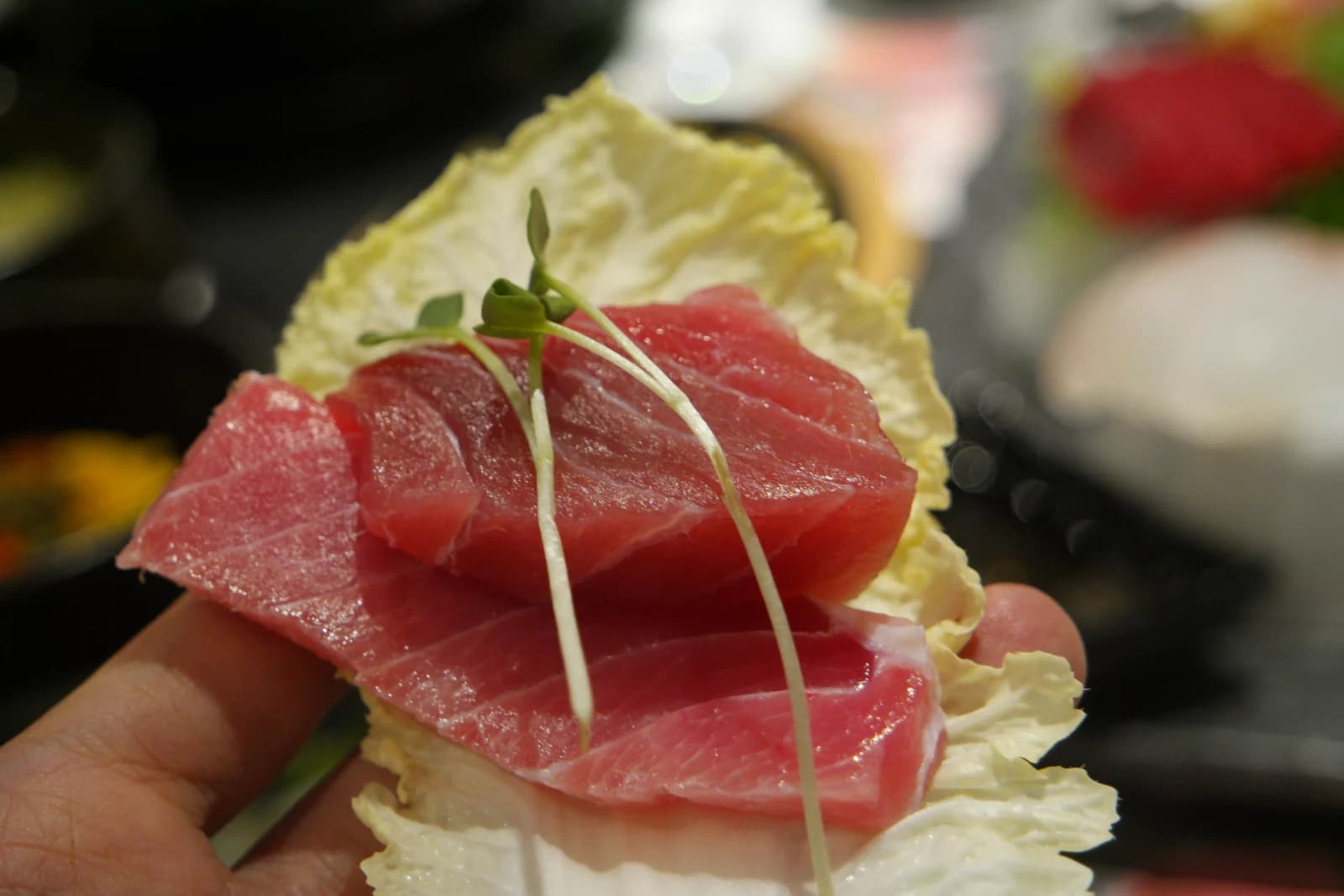 Tuna sashimi placed on a napa cabbage leaf wrap with micro greens on top, Korean ssam style