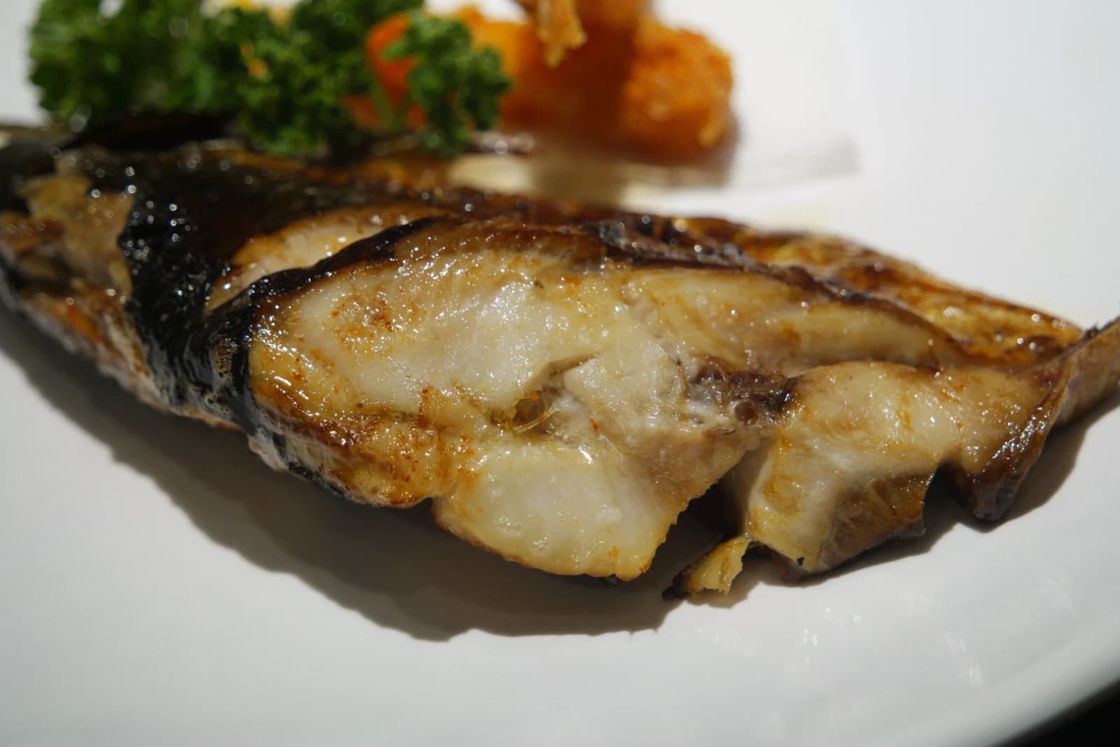 Close-up of grilled mackerel with crackled skin and glistening oil between the flakes