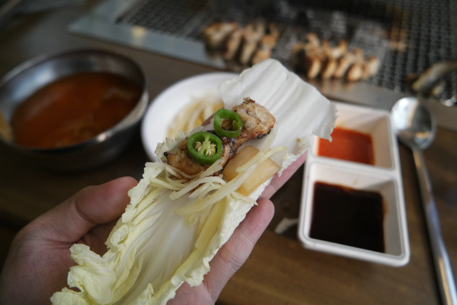 배추 잎 위에 장어 생강 청양고추를 올려 쌈을 싸는 모습 - 한국식 장어 먹는 법 | 하이제이에스비