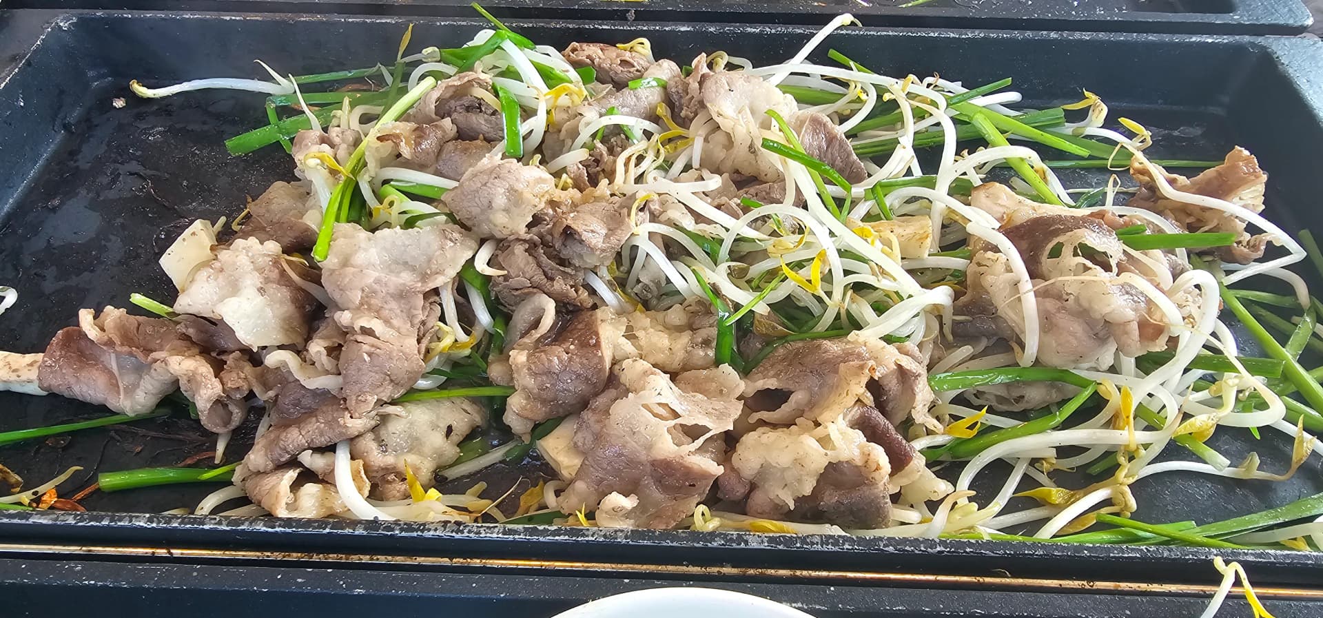 숙주나물과 부추 위에 차돌박이를 올려 볶듯이 굽고 있는 불판 | 하이제이에스비