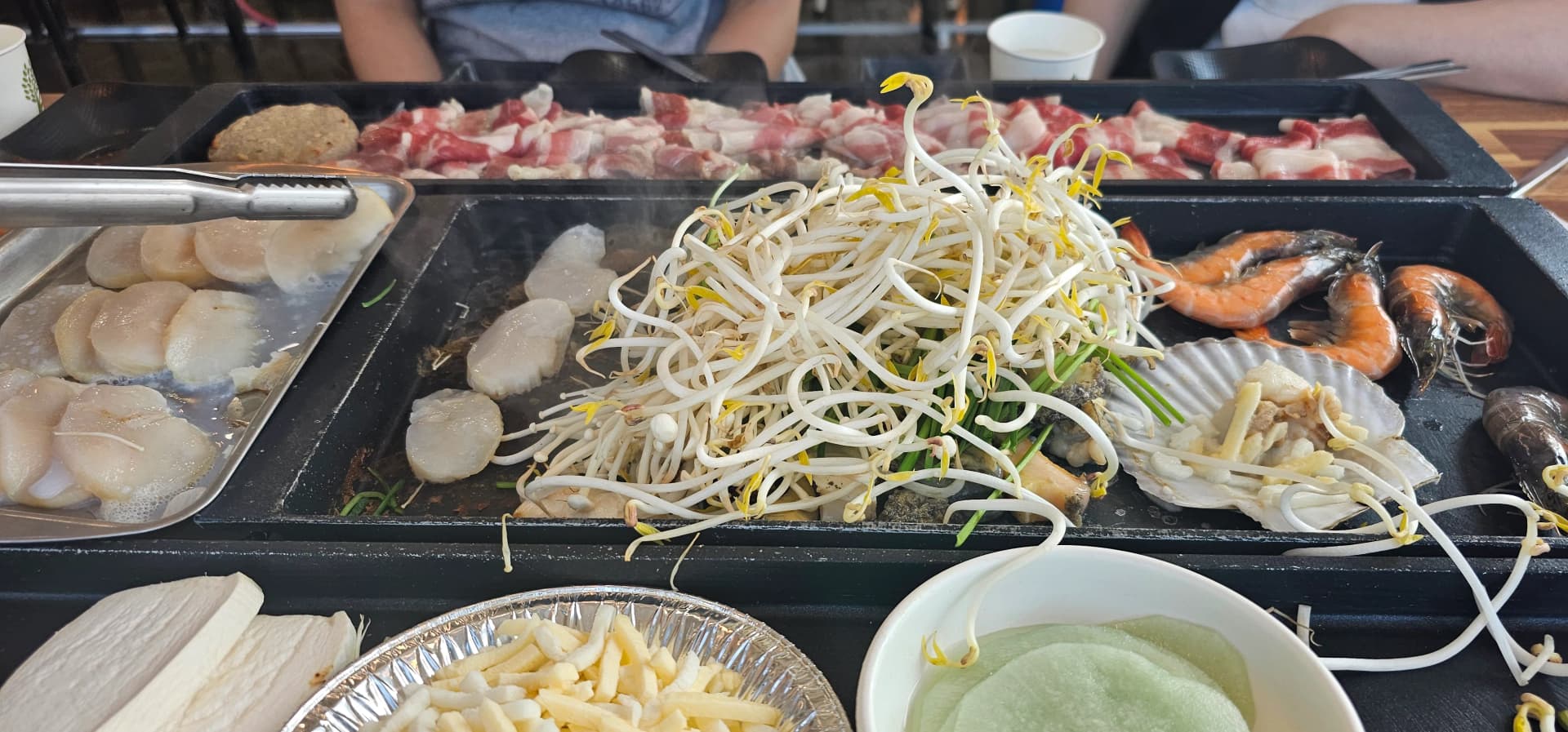 차돌박이 기름이 지글거리고 숙주나물에서 수증기가 올라오며 새우가 익은 불판 전경 | 하이제이에스비