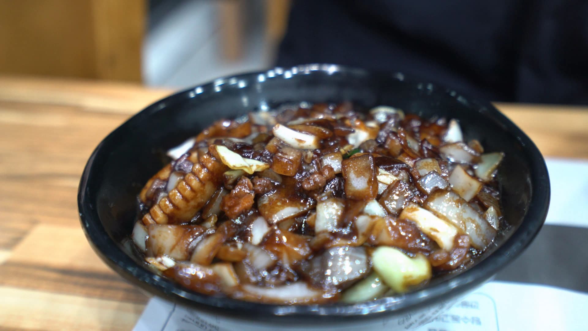 لقطة قريبة لصوص كانجاجانغ كثيف، قطع بصل كبيرة ولحم واضحة مغروسة في الصوص الأسود الداكن