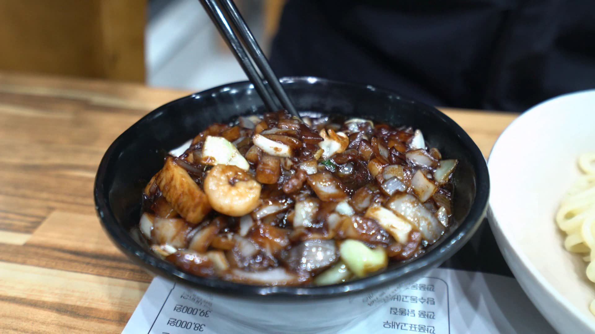 وعاء صوص كانجاجانغ وبجانبه يبان طرف وعاء النودلز، الصوص فوقه بصل مقرمش ولحم مقلي طازج