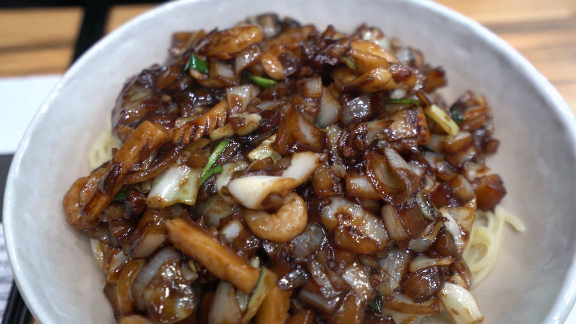 لقطة مقرّبة لحشوة الكانجاجانغ، بصل نصف شفاف ولحم مغلّف بطبقة رقيقة لامعة من صوص التشونجانغ الأسود