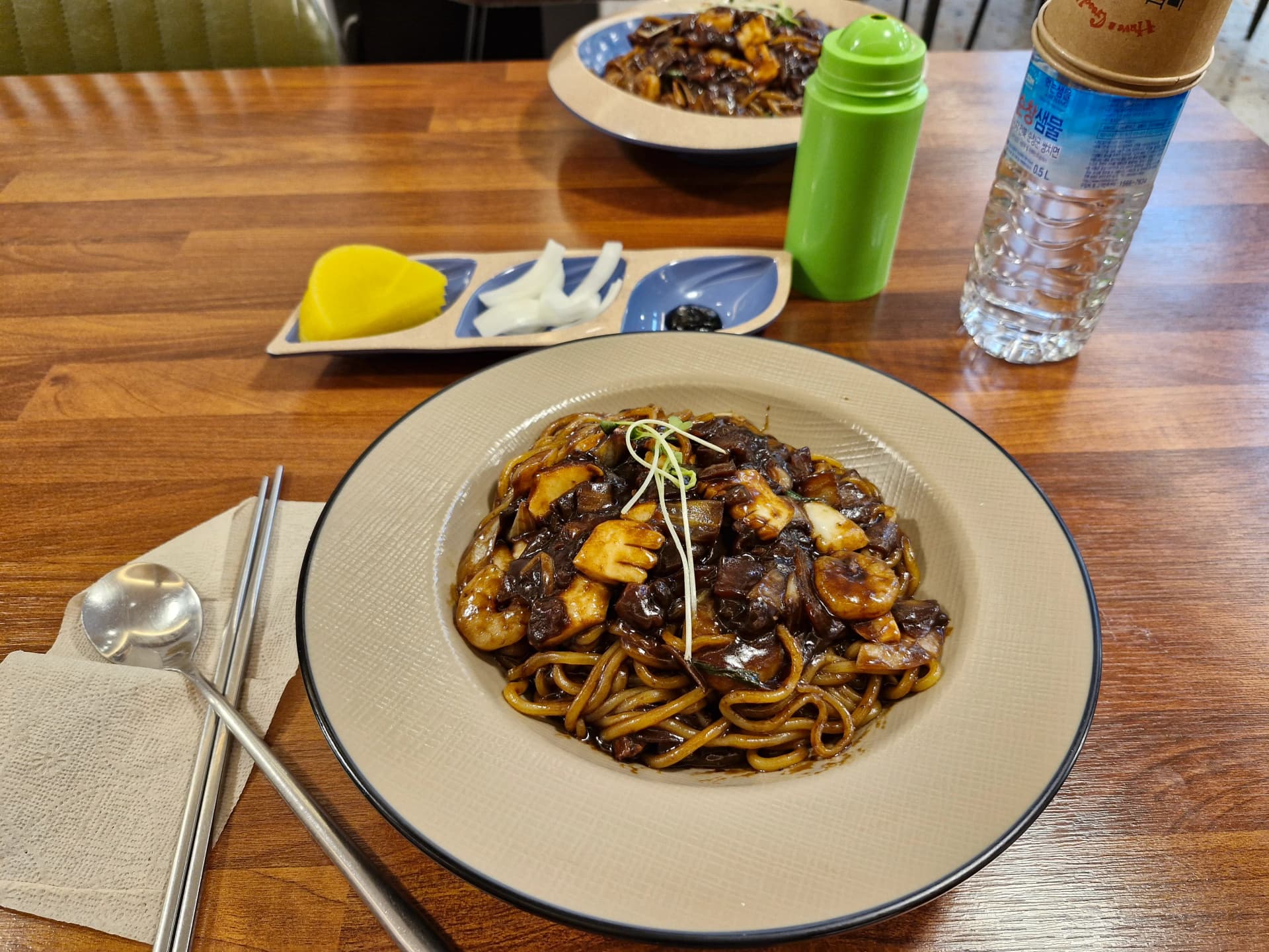 طاولة مطعم كوري صيني كاملة عليها سامسون جاجانغ وكانجاجانغ مع دانموجي وبصل مخلّل وقوارير ماء