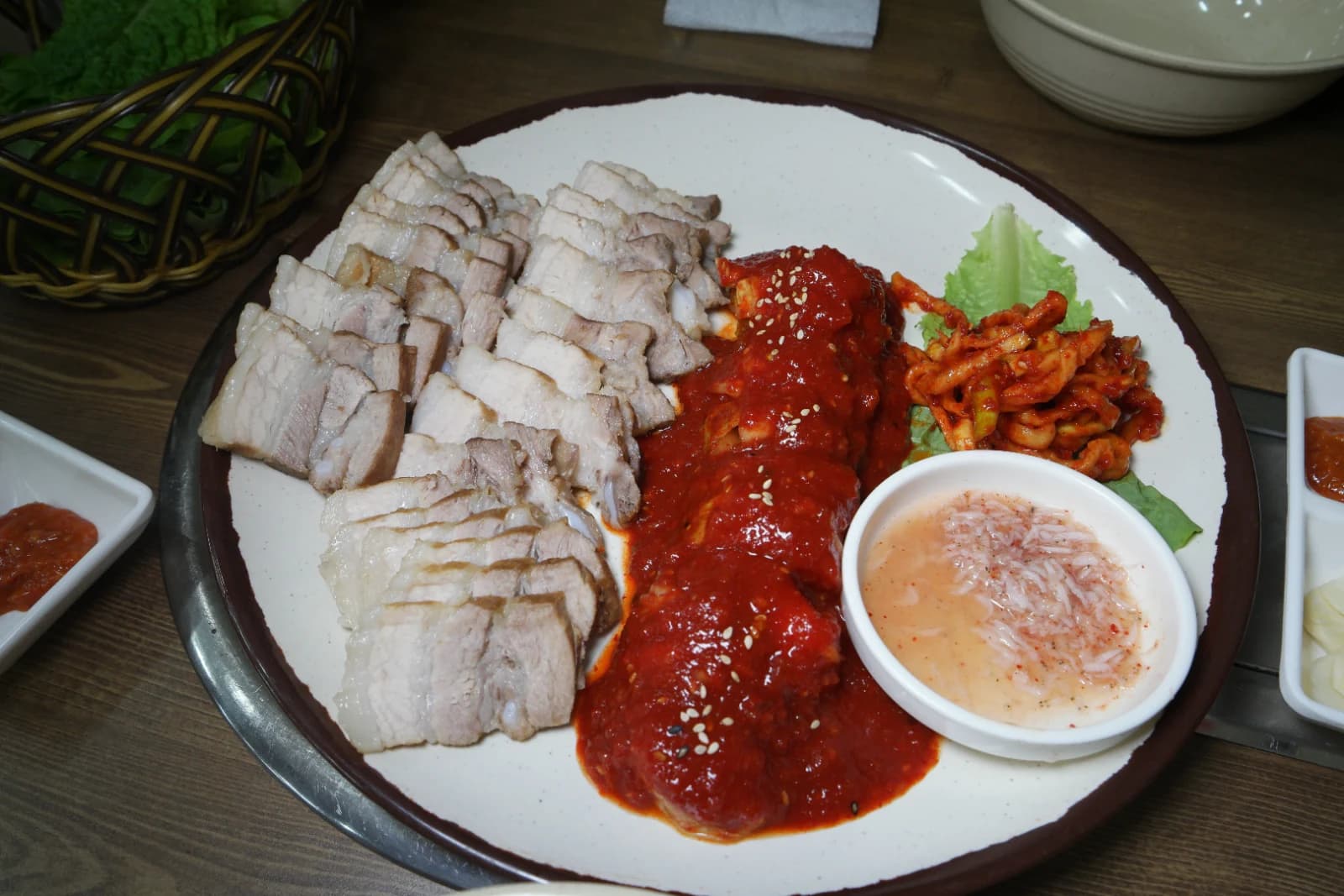 Bossam platter spread across the table with kimchi in the center and sliced pork on both sides